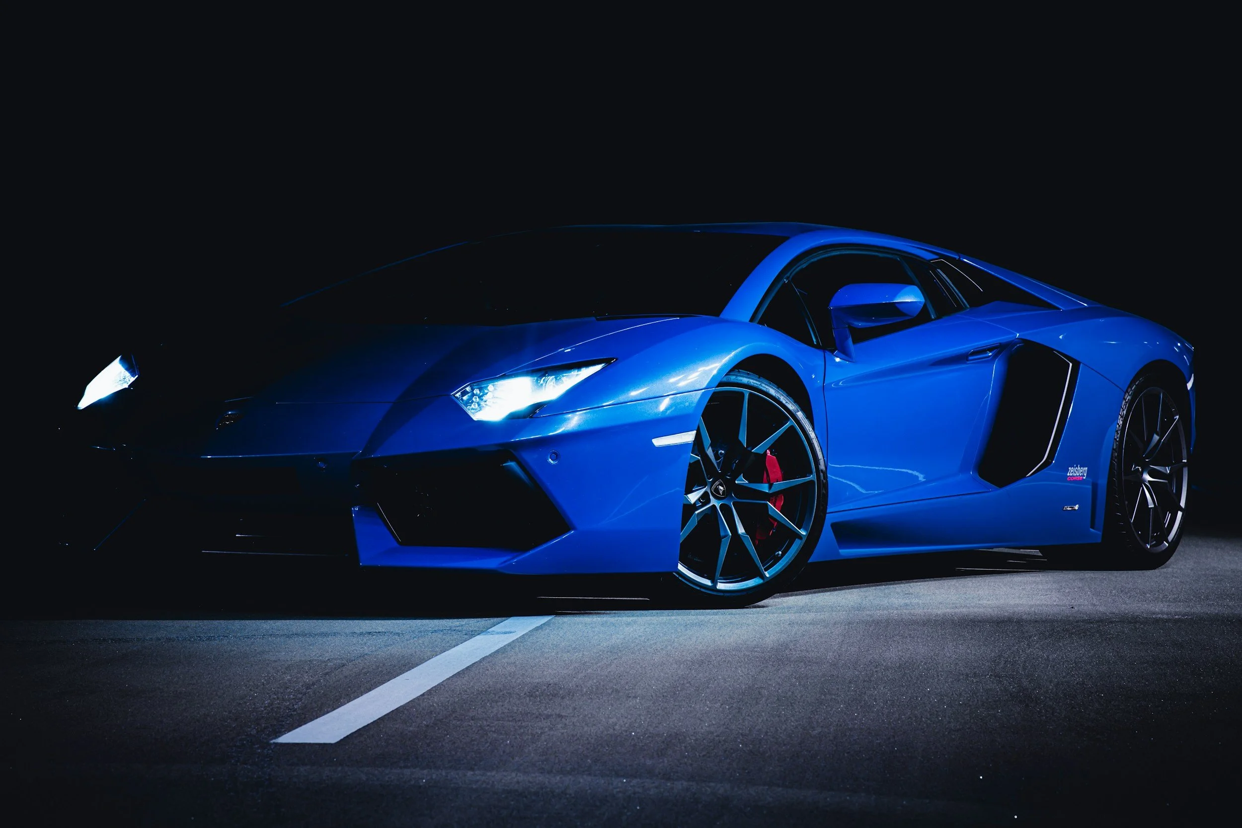 blue sportscar taking picture on cement road with white line