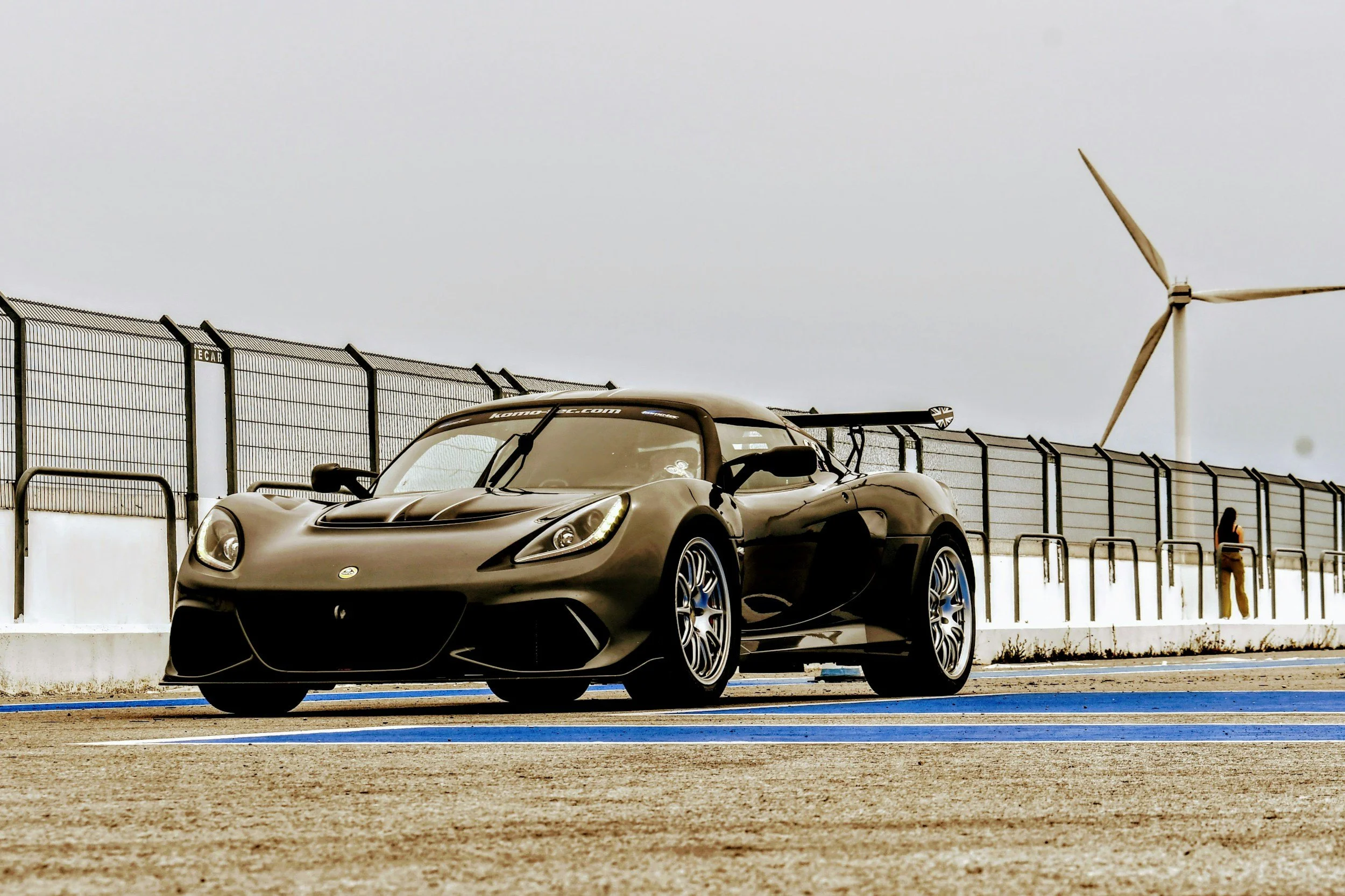 black 2 door sportscar driving over bridge white sky