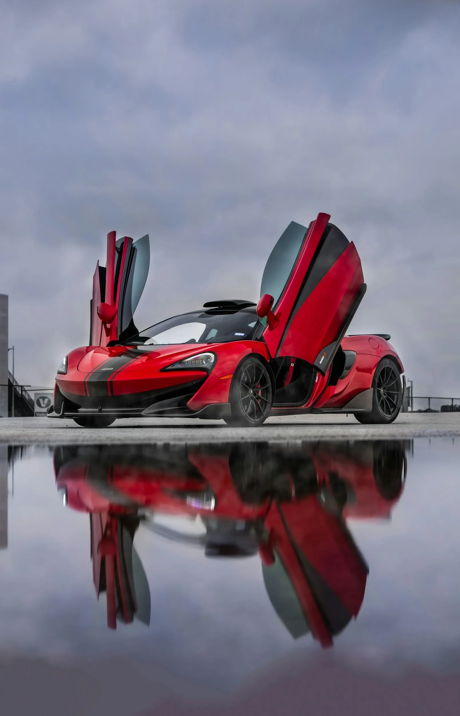 red car will gull wing scissor doors up for pictures on cement road