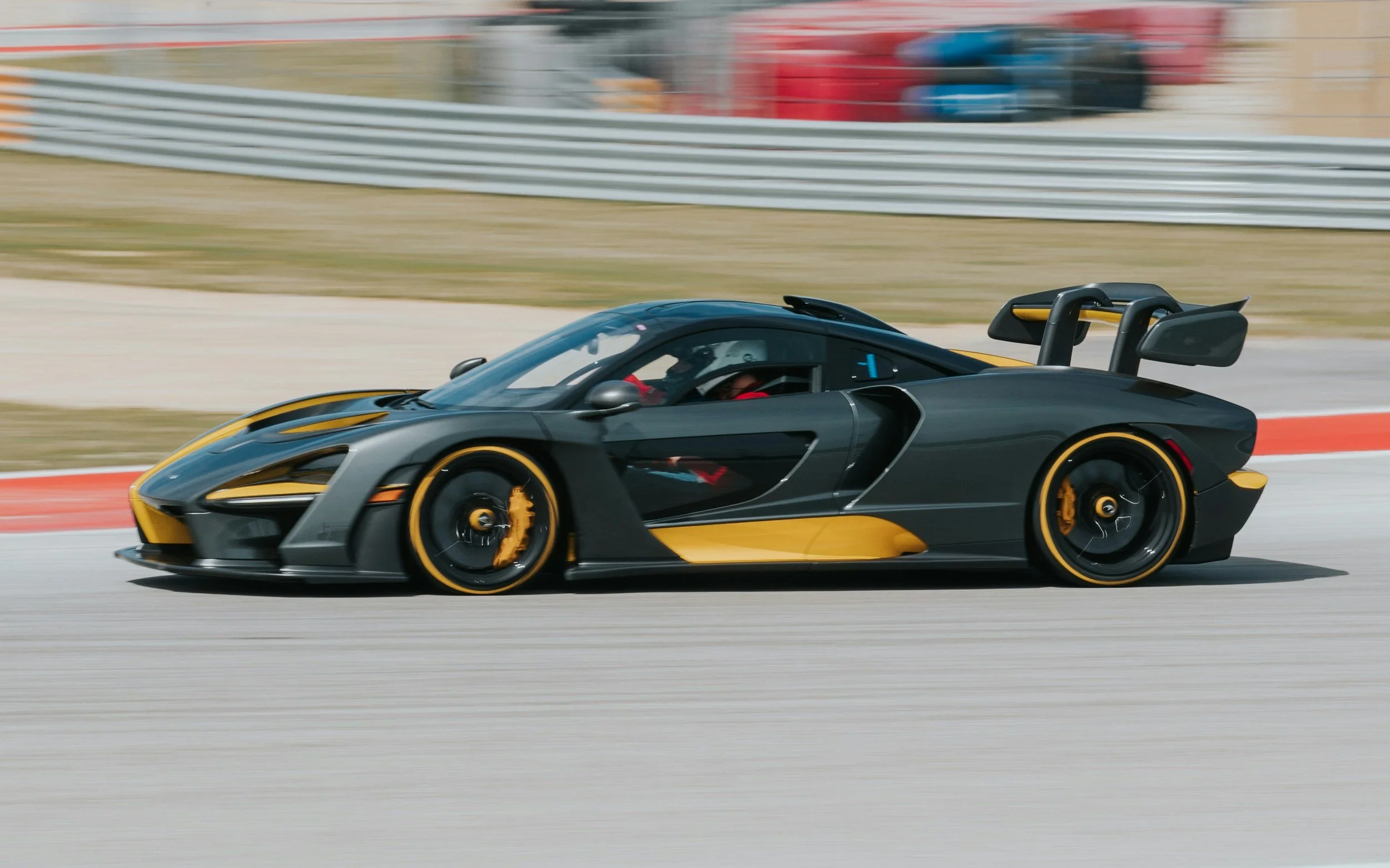 black sports car with yellow accents and black wheels yellow brakes racing on track