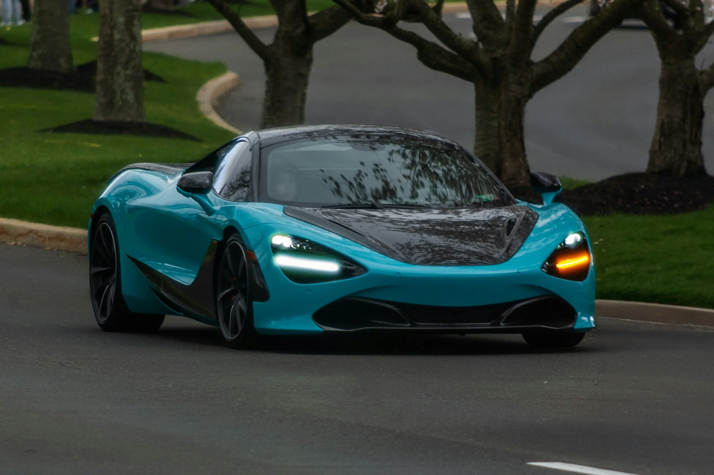 bluish teal color car driving down long driveway or road in the country side