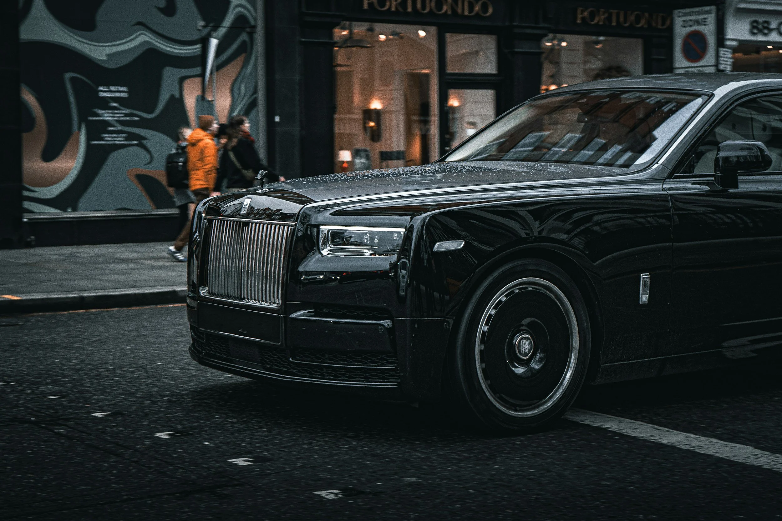 front end of a black sedan driving in town busy stores