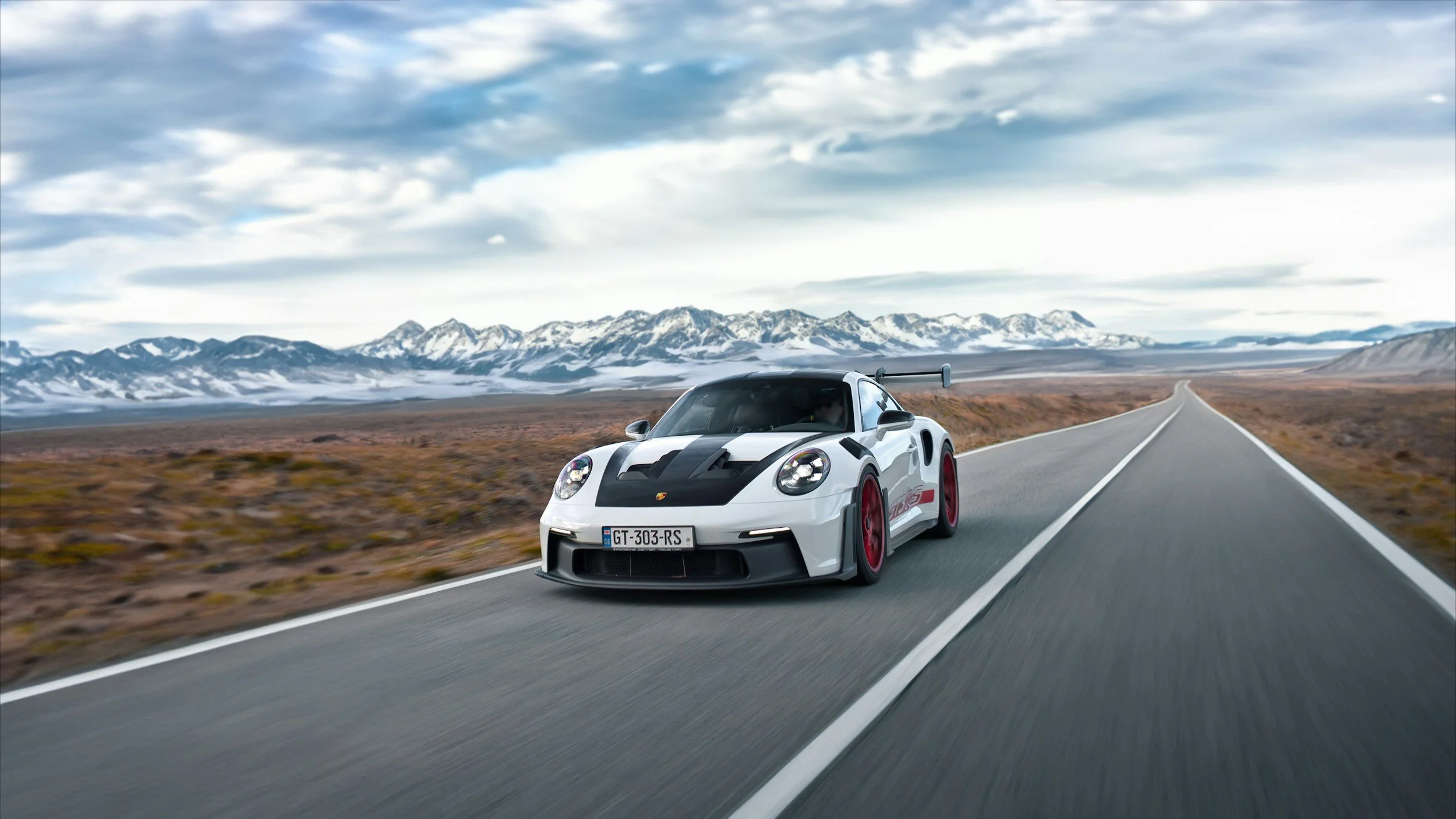 with 2 door sports car driving on country road surrounded by mountains black accents on car