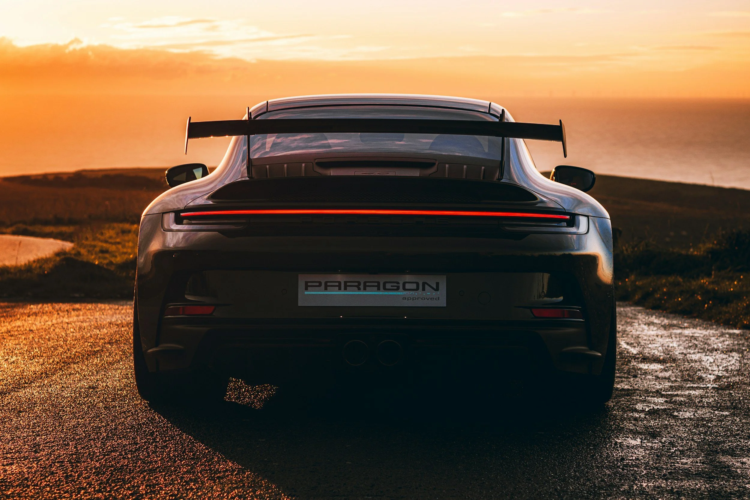 rear end of a car on road very wide with wide wheels and tires cement with sunrise