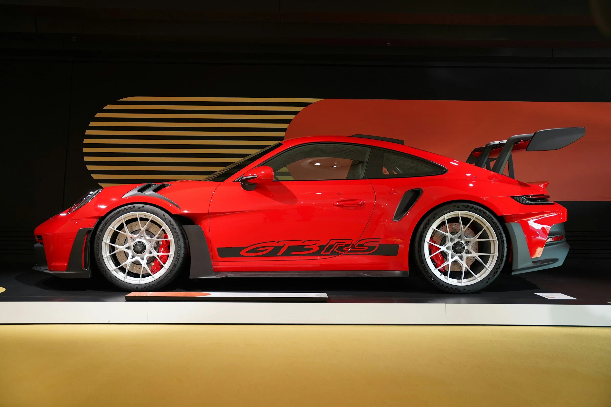 red porsche 2 door car on auction stage being auctioned or pictures taken