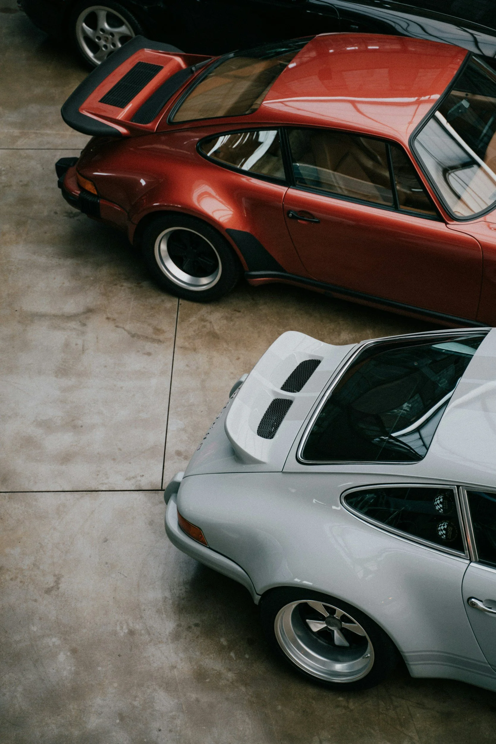 2 cars white and burnt orange color in showroom or garage