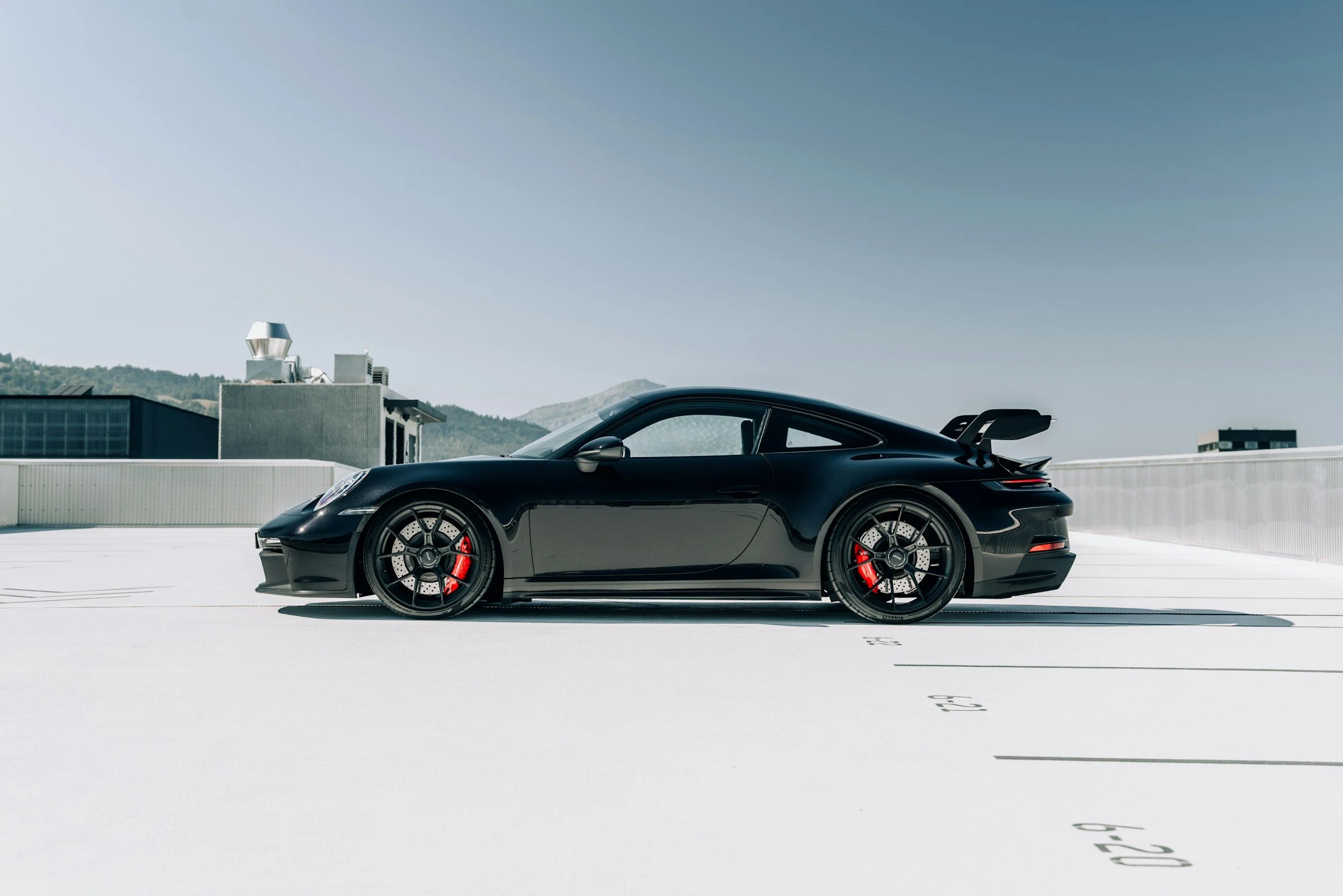 black car with red brakes parked on rooftop white cement