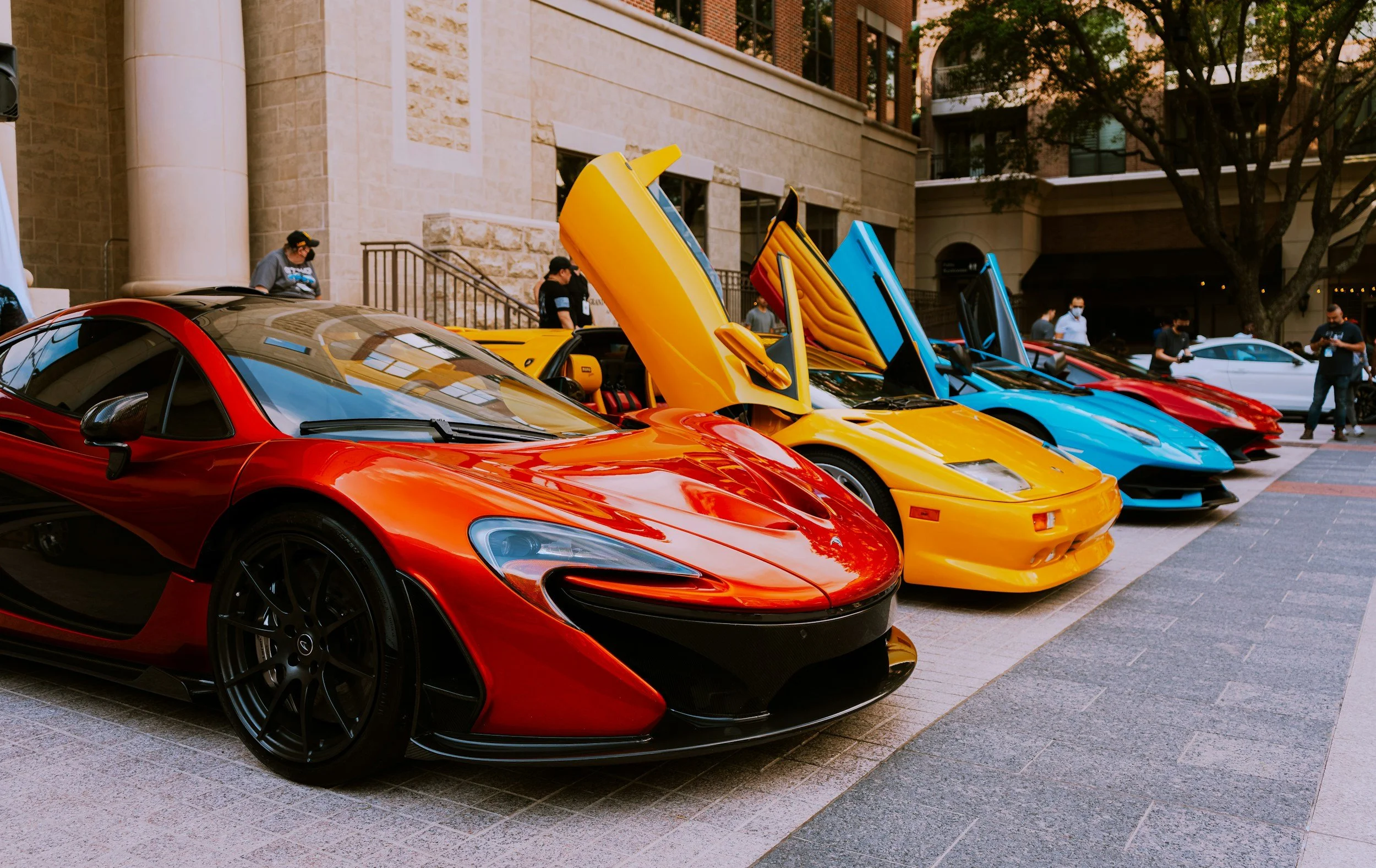 5 sports cars in a row with hoods up in a museum or car show
