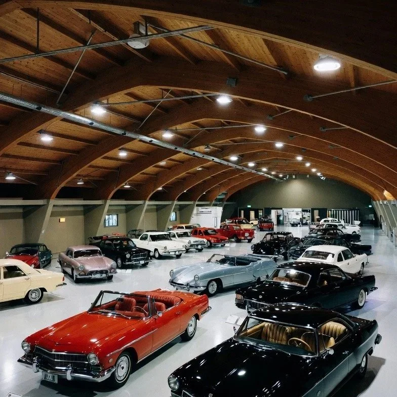 green walls wood arching roof nice cute small car museum with a mix of older classics, new age bond type cars in white, red, black, cream, cars with pnw car smart