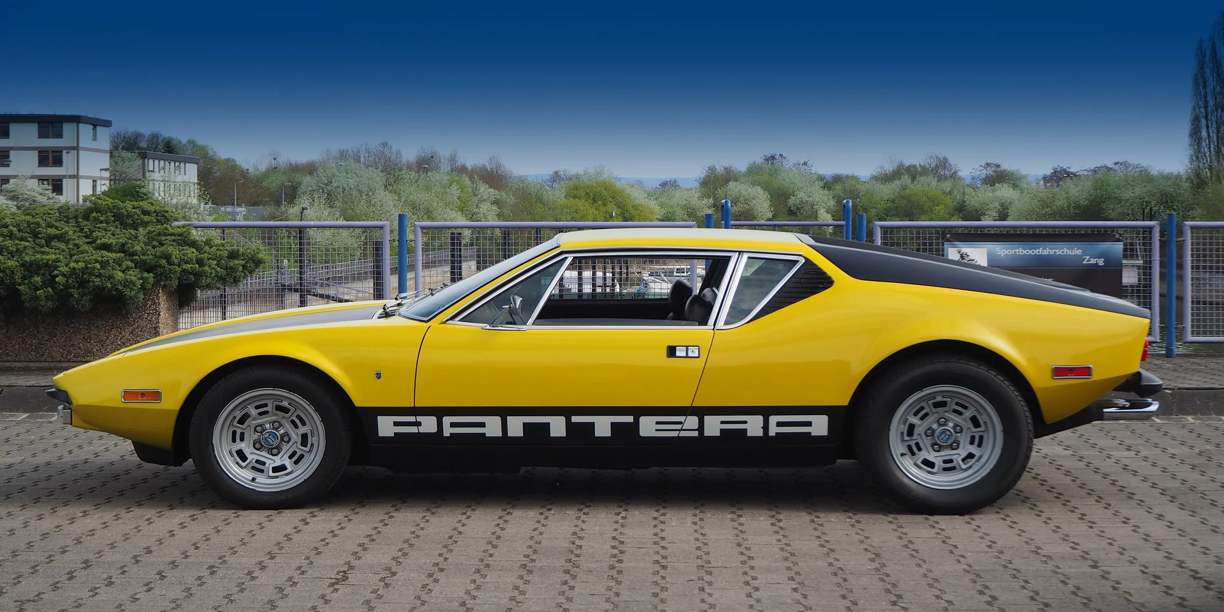 yellow sports car parked on cobblestone road 2 door