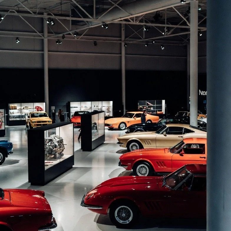 orange , tan, yellow, blue cars in large room for display with engines