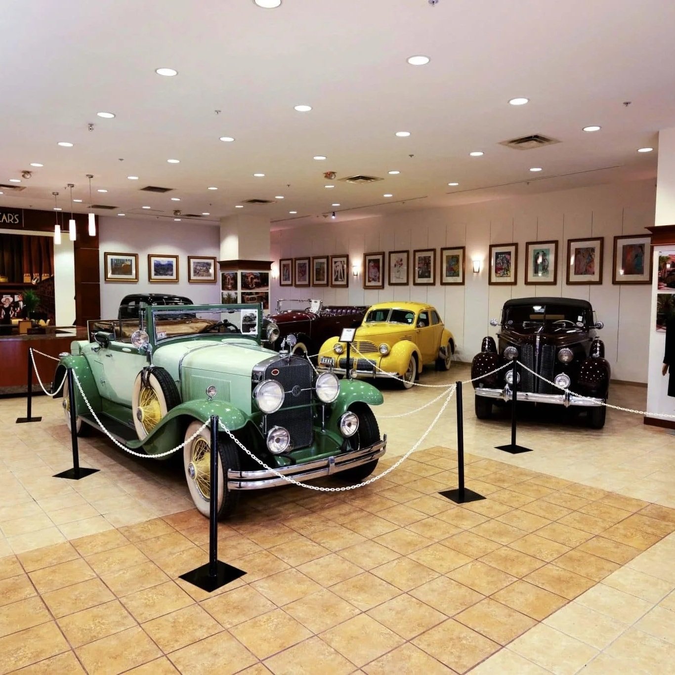 2 tone green, bright yellow, black, maroon chain roped off sections in car museum show room with pnw car smart