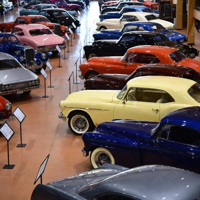 silver, gray, blue, pink, blue, candy apple, white black grey cars on a wood floor with stands explainging car and information on them with pnw car smart