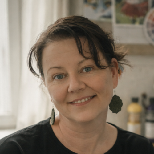 Penny Apple, smiling in her art studio at Penny Apple Studio, with colourful pet portraits displayed in the background. Friendly and approachable profile picture in a round frame with the studio logo.