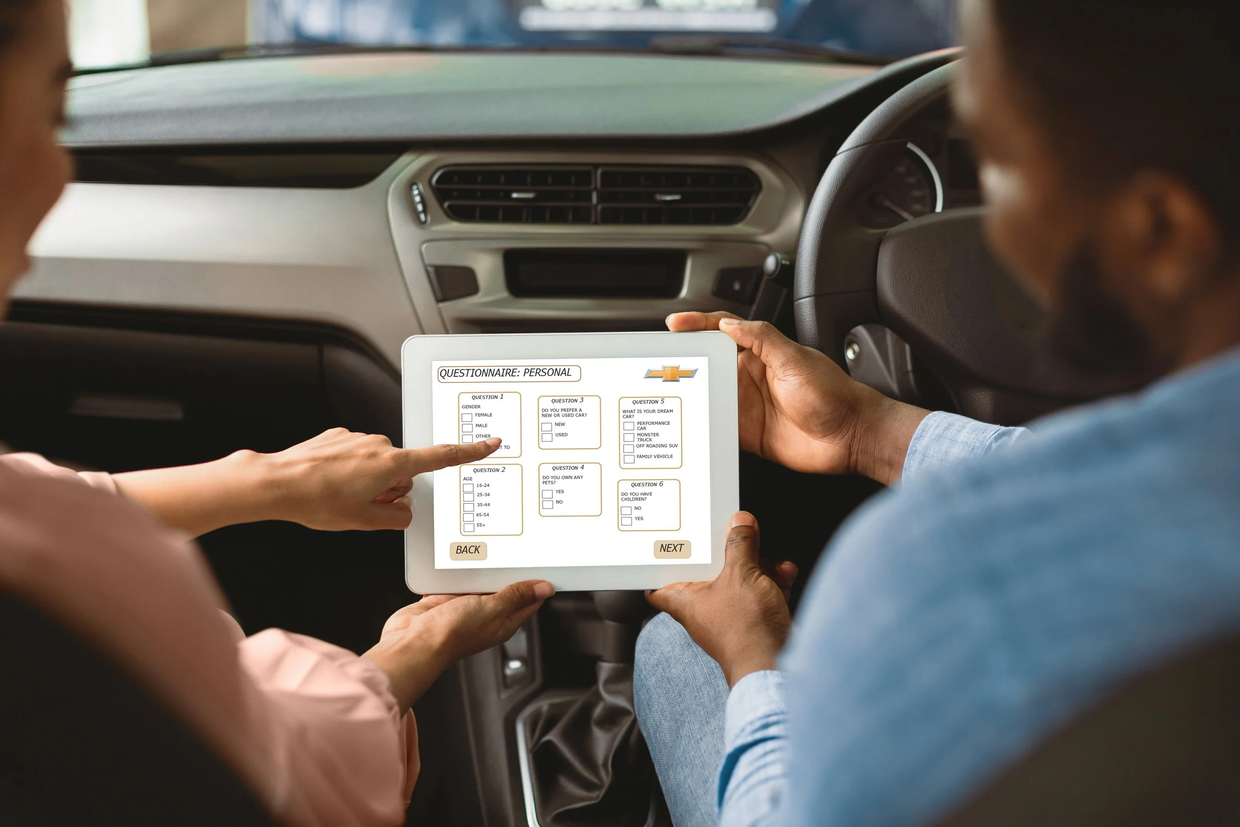 Two people sitting in a car holding a tablet displaying a personal questionnaire with questions about gender, age, pet ownership, and preferences. The person on the left is wearing a light pink top, and the person on the right is dressed in a light blue shirt. The tablet screen has a Chevrolet logo on the top right corner.