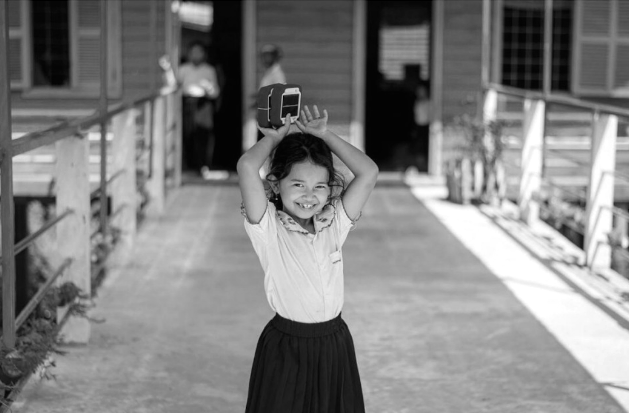 A young girl proudly displaying a solar-powered device, representing energy access, community empowerment, and the impact of renewable energy solutions in addressing energy poverty.