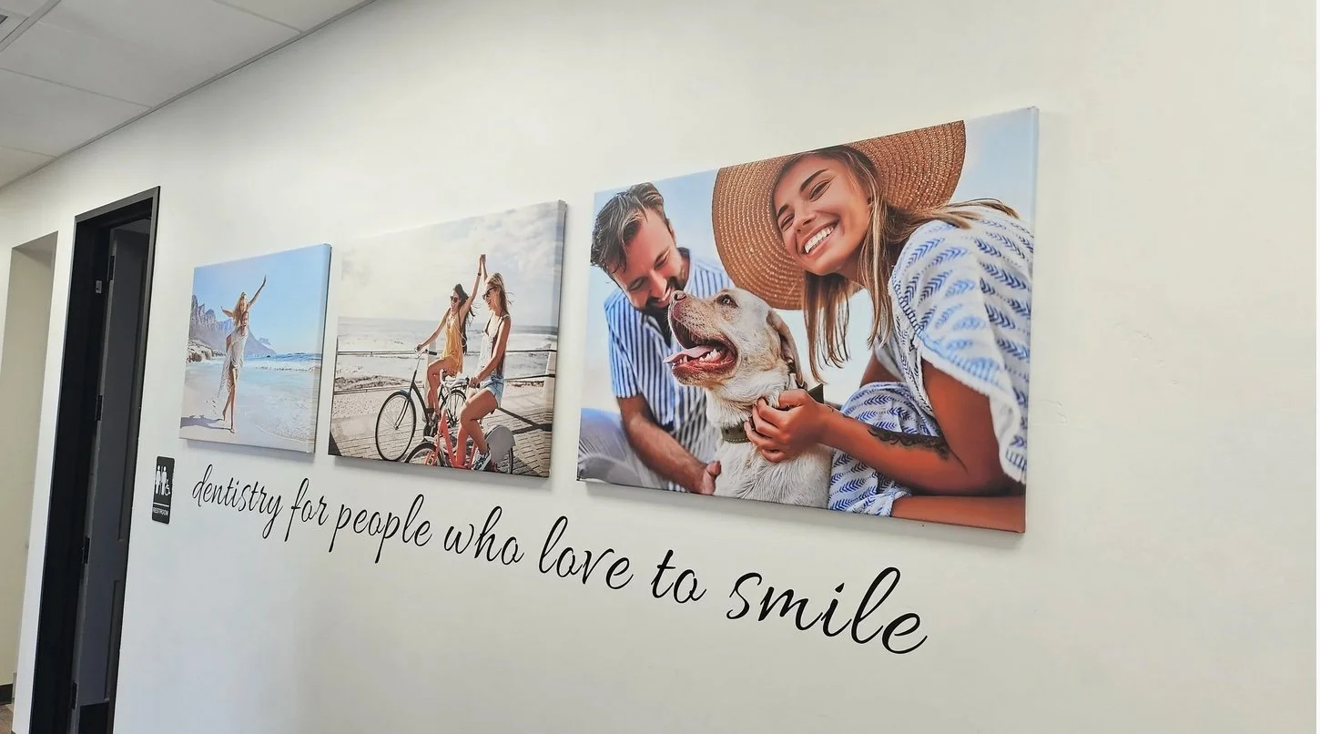 Wall with three large photographs of smiling people and a dog, and a quote that says 'dentistry for people who love to smile'.