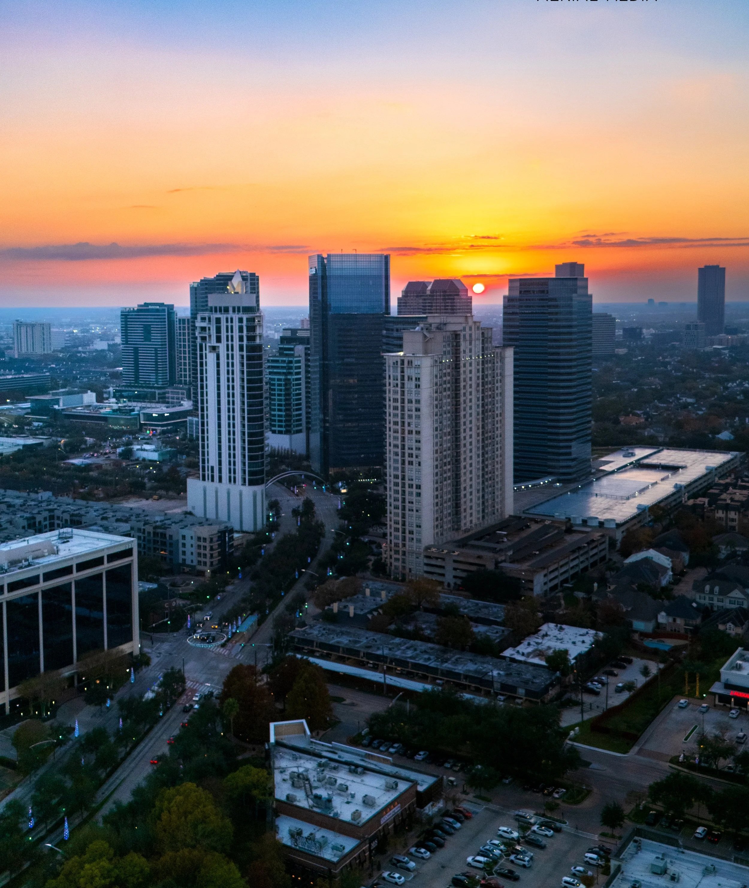 City skyline at sunset with tall buildings and a partially cloudy sky.
