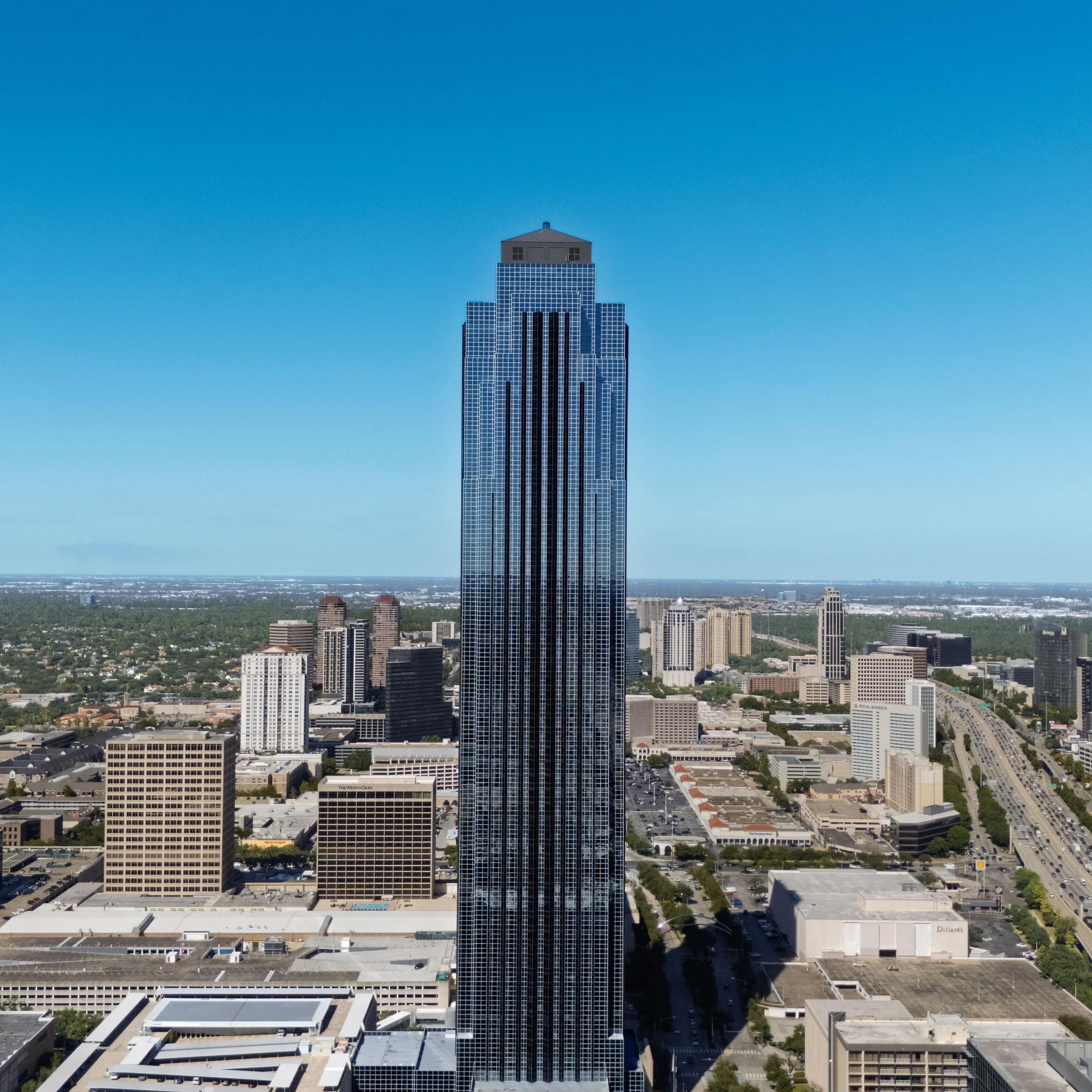 Tall skyscraper in downtown Atlanta with surrounding buildings and a clear blue sky.