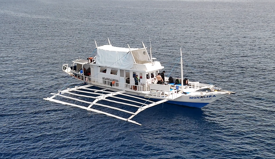 A white banca boat named Monaliza floating on the ocean.
