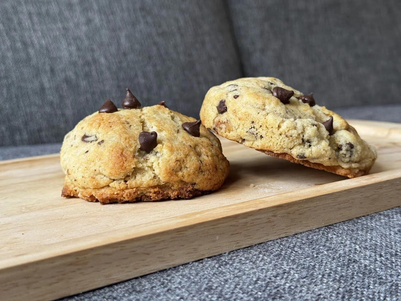 Dos cookies keto con chispas de chocolate sobre una tabla de madera.