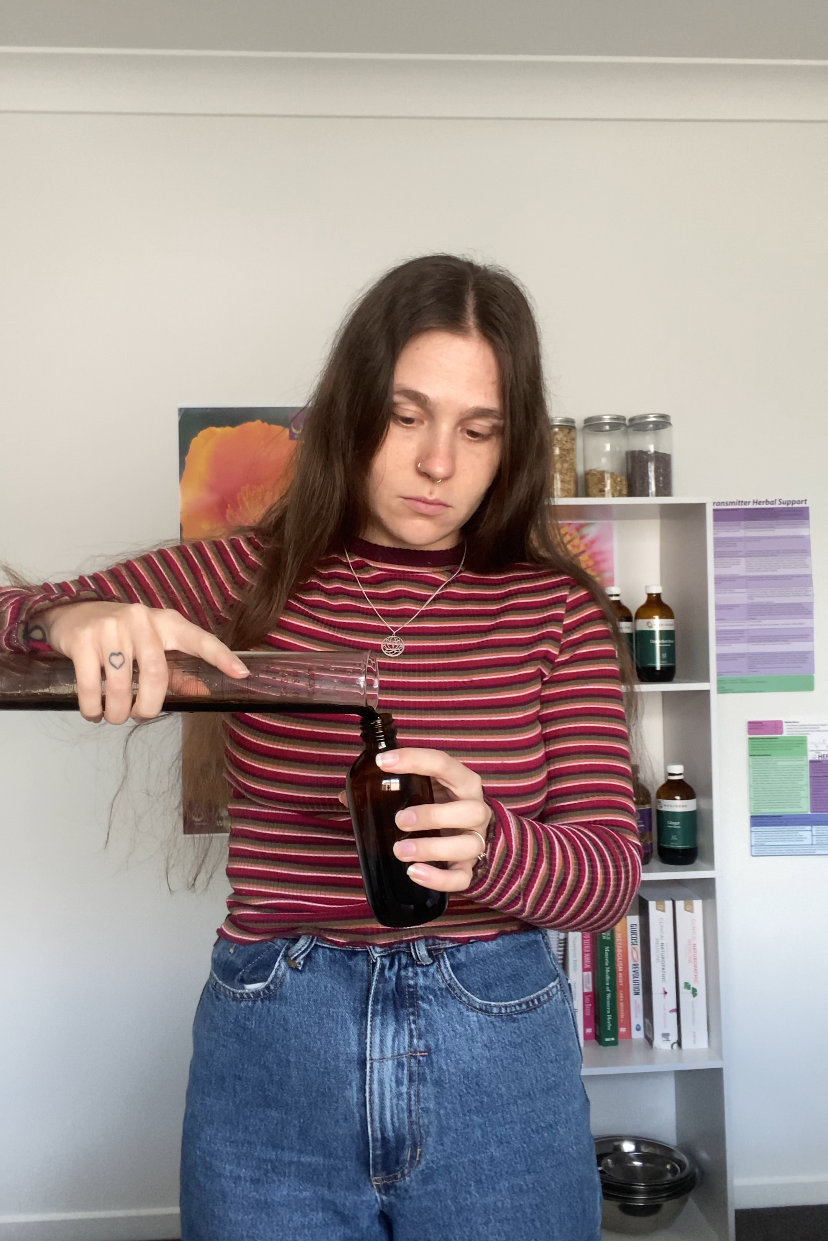 Naturopath specialising in POTS carefully pouring a herbal medicine in her clinic workspace”