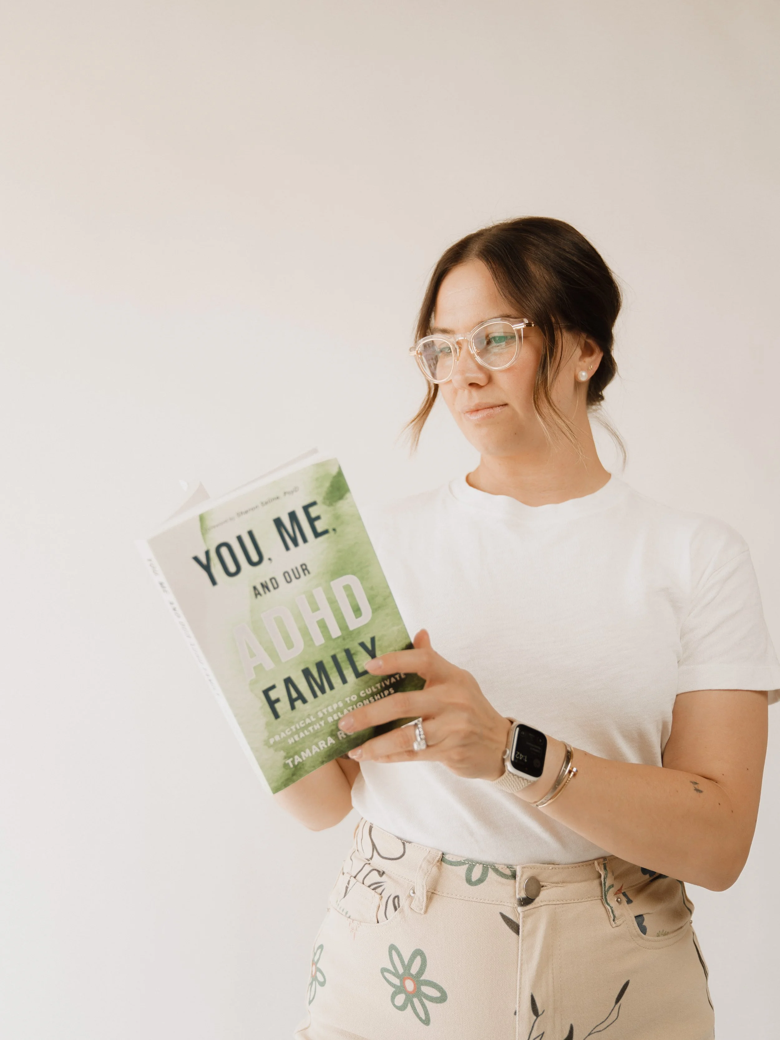Woman with glasses standing and reading a book about ADHD and family