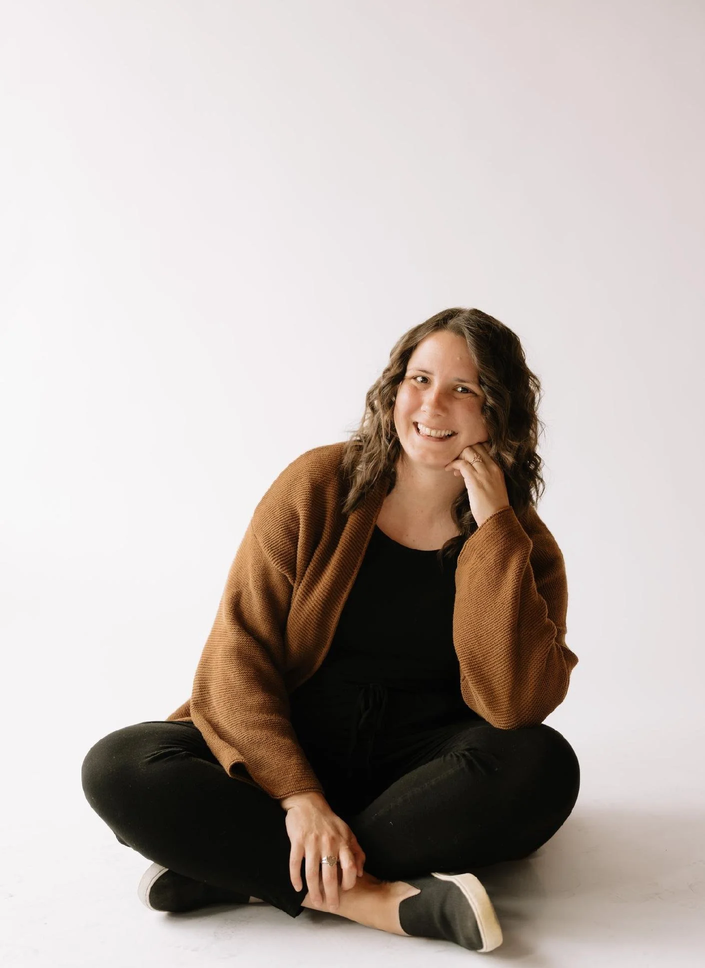  Phoenix Therapist A woman with long brown hair smiling in front of a trellis with pink bougainvillea flowers.