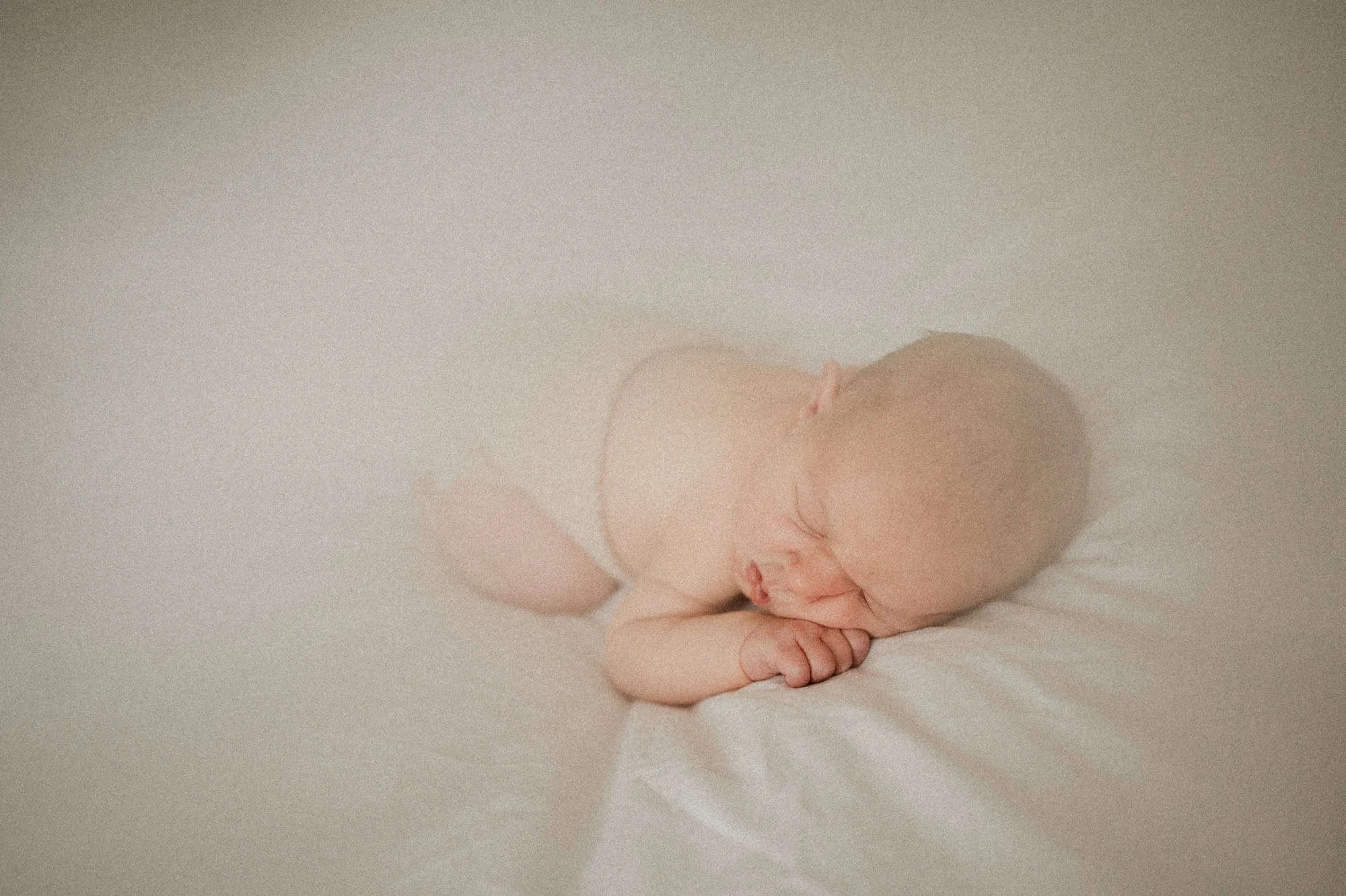 Best newborn photographer in Zürich captures a peaceful moment of a newborn baby sleeping on a bed, showcasing delicate details and timeless beauty in newborn photography