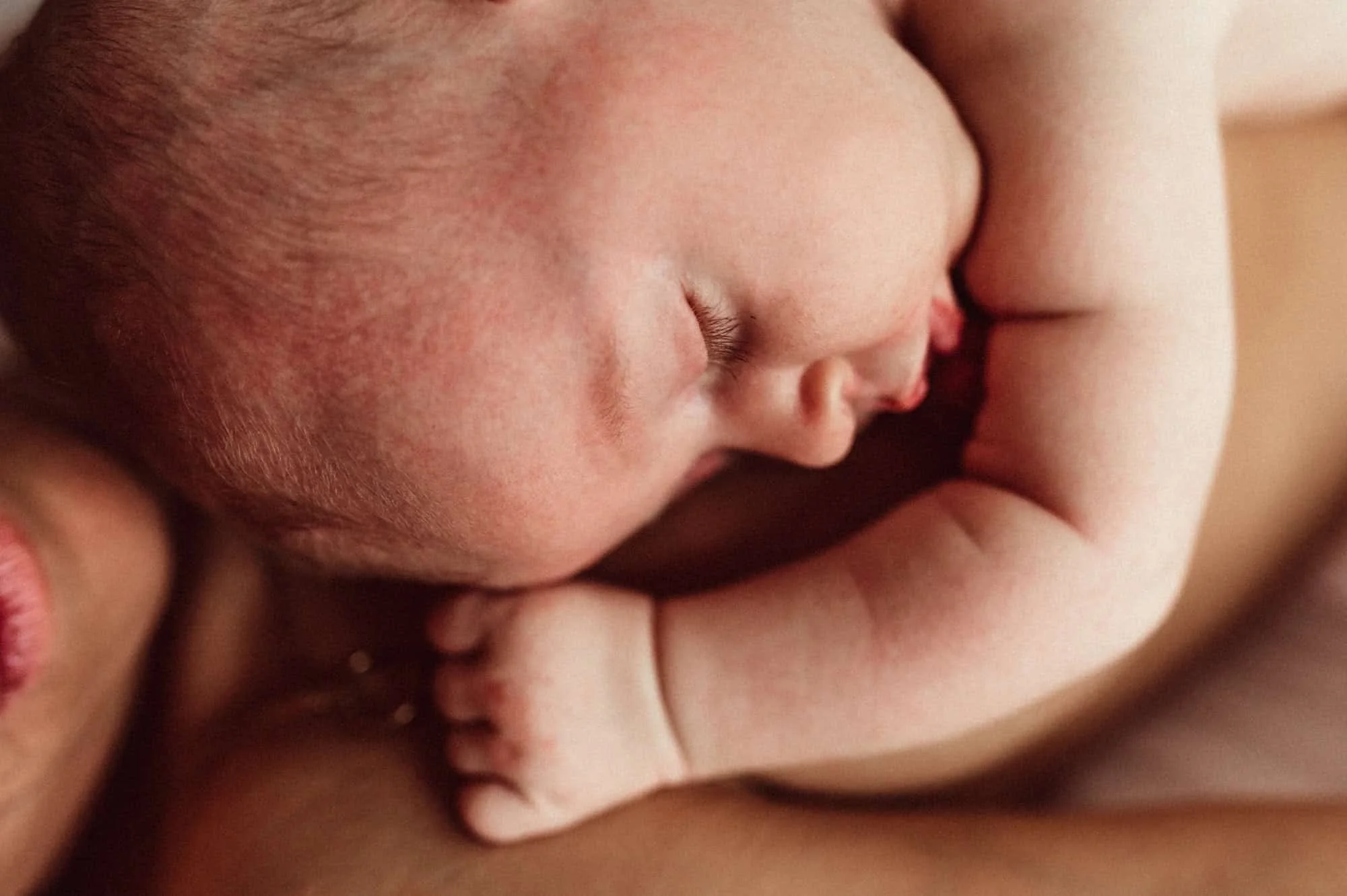 Newborn cuddling with mother in a tender skin-to-skin moment, captured by the best family photographer in Zürich, showcasing love and connection.