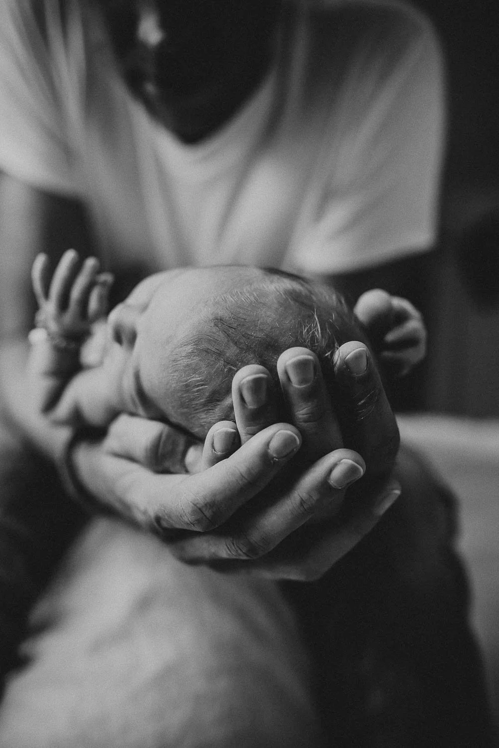 Father holding his baby in soft light during an intimate and personal newborn session at home in Zurich