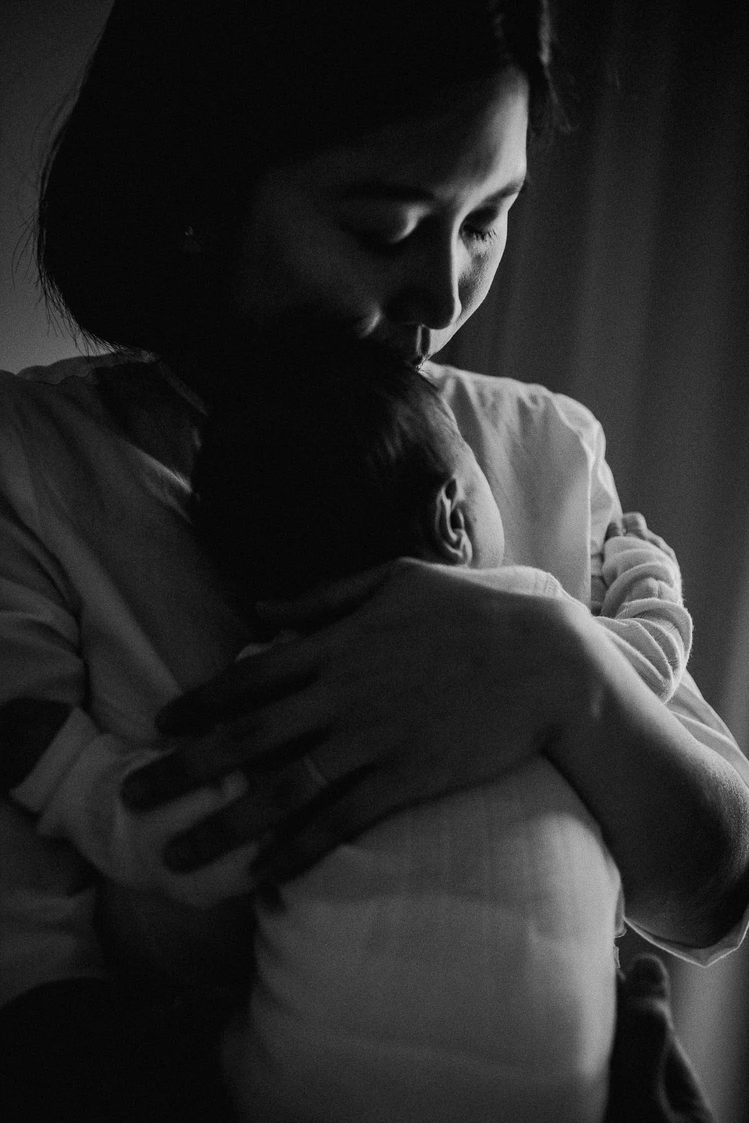 Nahaufnahme einer Mutter, die ihr Baby zärtlich auf den Kopf küsst.