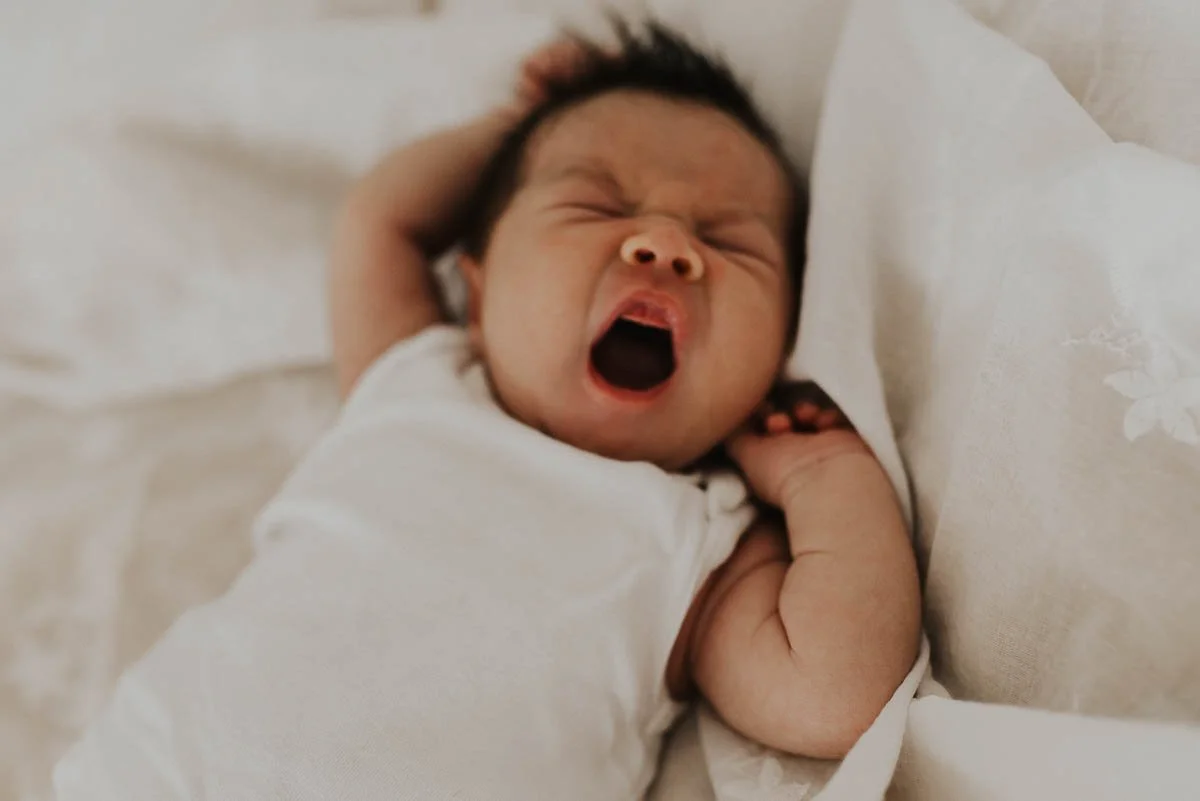 Neugeborenes streckt die Arme nach dem Aufwachen in einer natürlichen Bewegung.