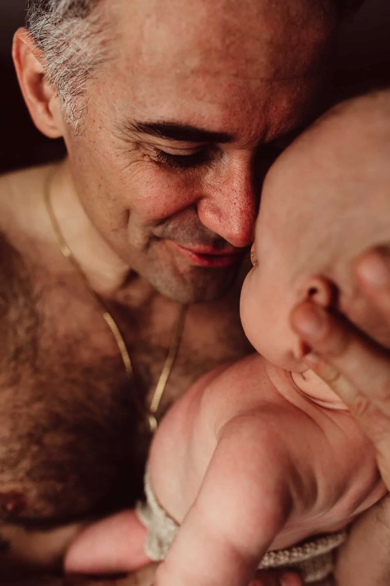 Father holding baby in a heartfelt moment, captured by the best newborn photographer in Zürich, highlighting love, warmth, and connection.