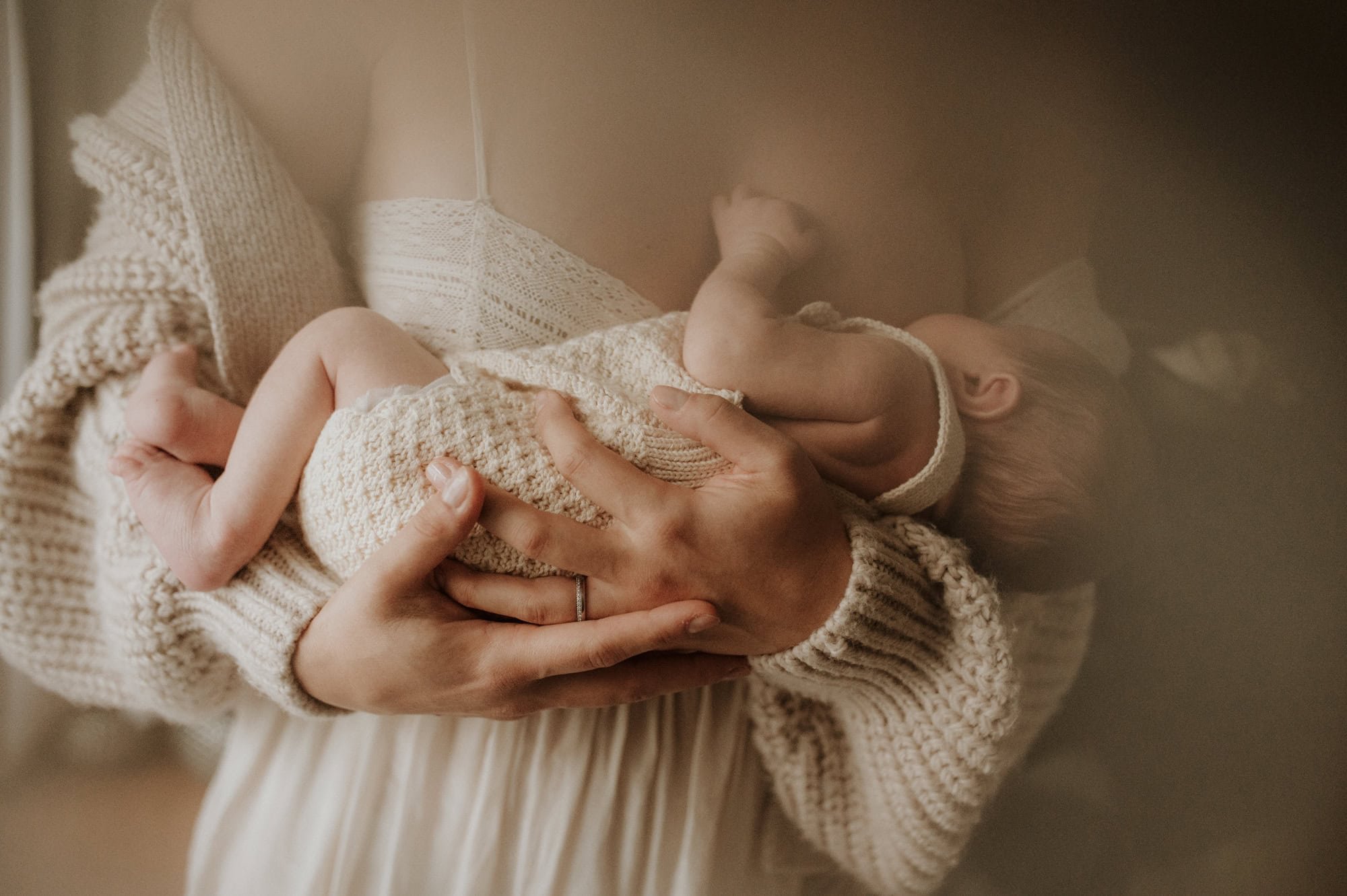 Newborn resting on mother’s chest during a quiet, dreamy moment with soft color tones.