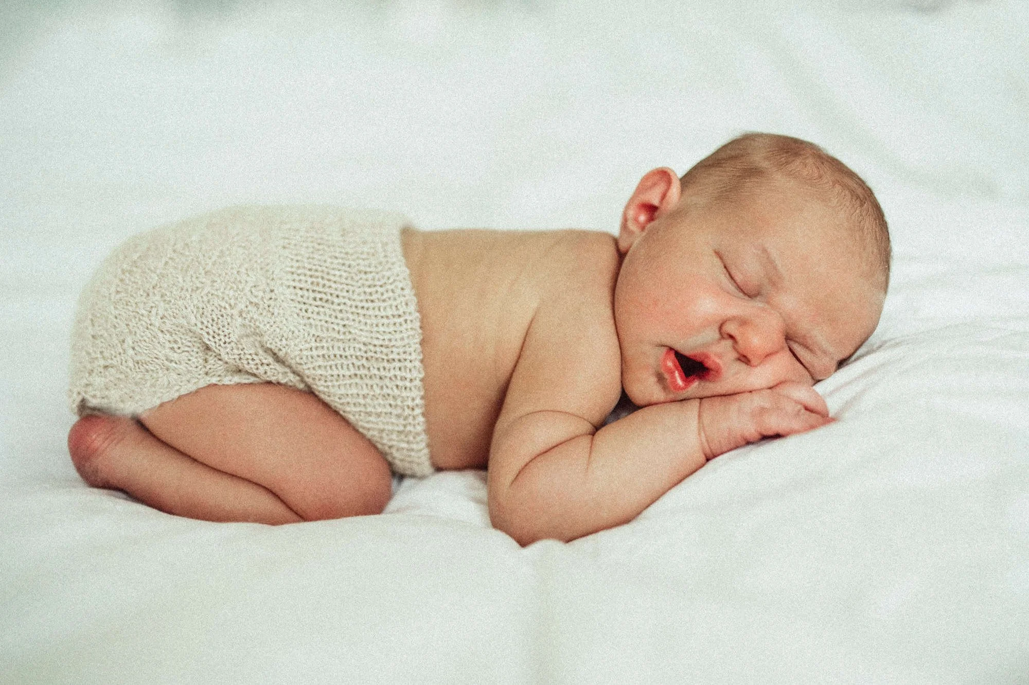 
Neugeborenes friedlich auf dem Bett liegend, festgehalten von einer Babyfotografin in Zürich, in einer natürlichen und liebevollen Szene.