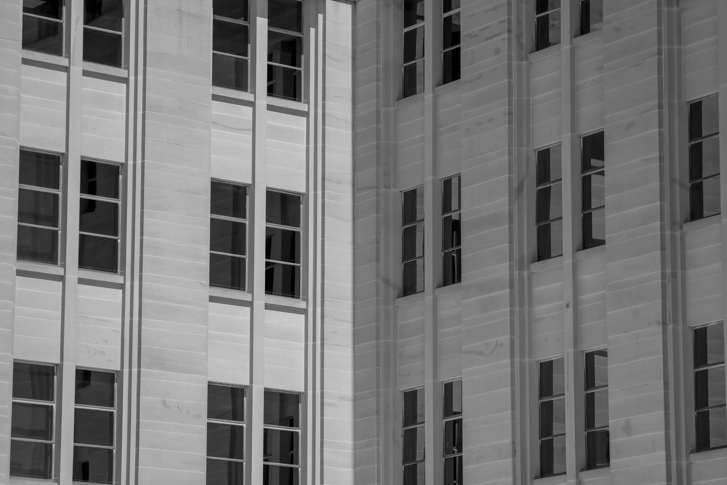 Close-up of a modern building facade with vertically aligned windows and concrete panels in black and white.
