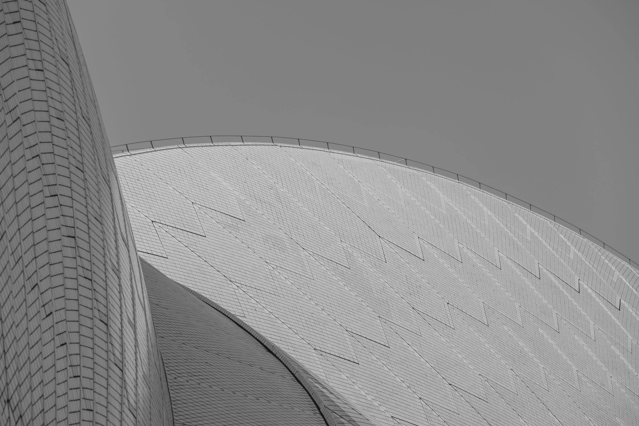Close-up of a modern, architecturally unique building with curved surfaces and tiled or panelled exterior, under a clear sky.