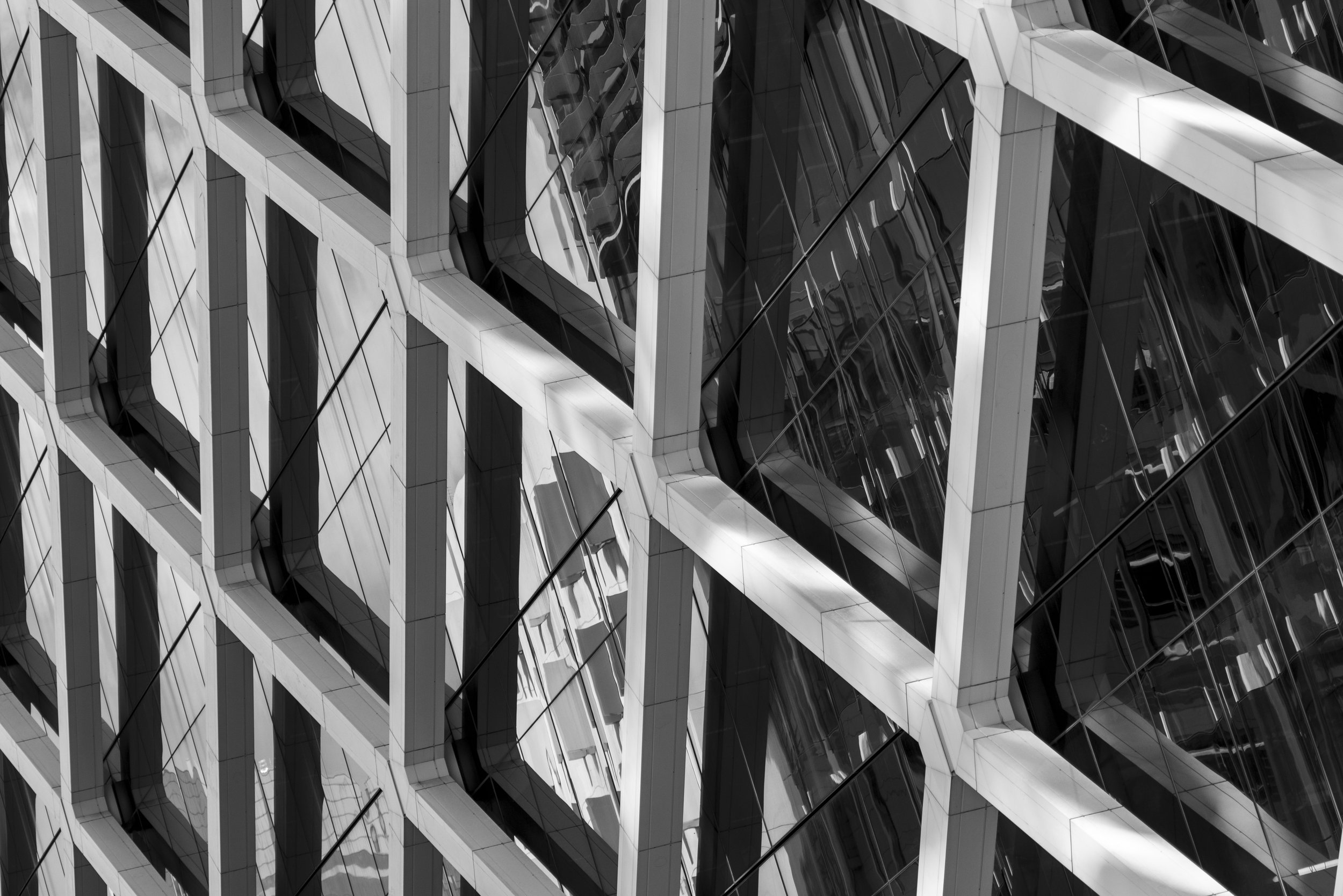 A modern building with glass windows and white structural elements creating a geometric pattern.