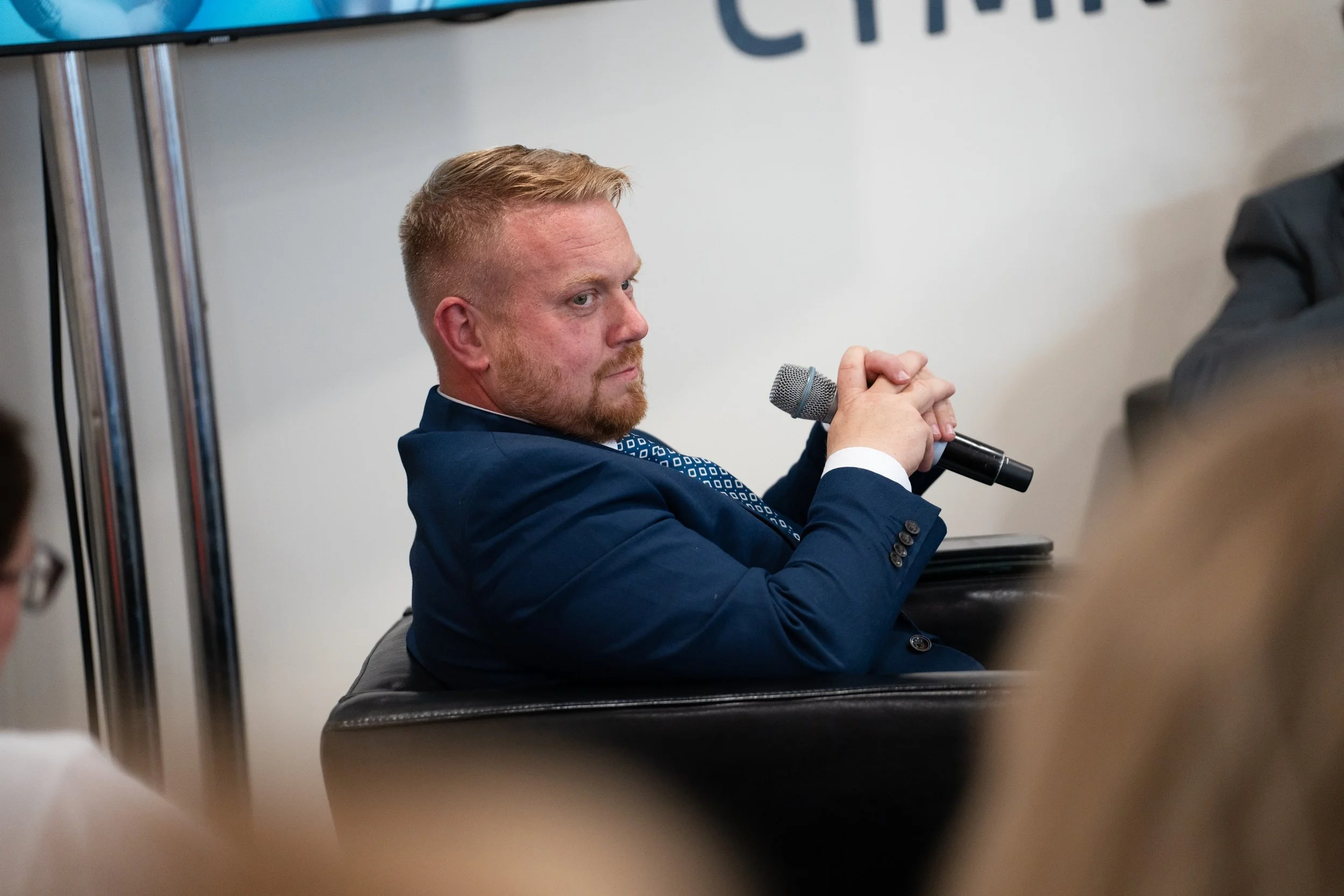 Rob Osborne moderating a live panel discussion, seated with a microphone while leading conversation at a professional event.