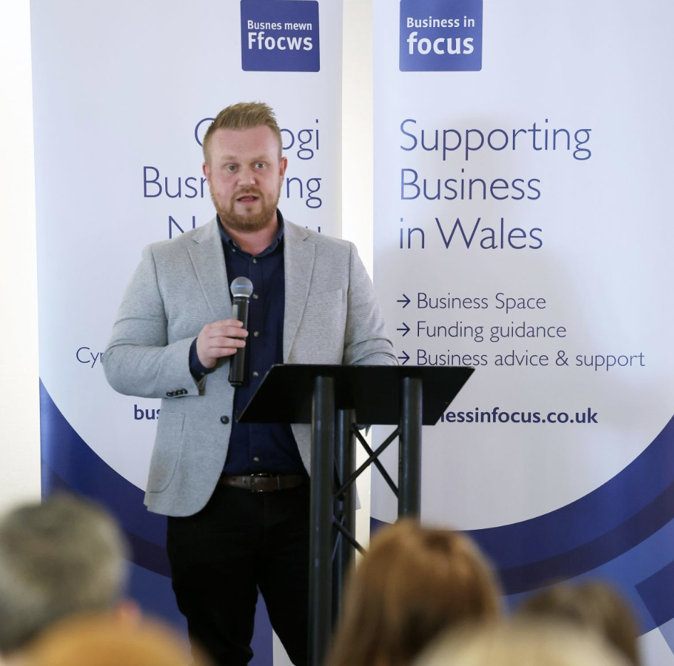 Rob Osborne speaking at a business conference, presenting from the stage to a professional audience.