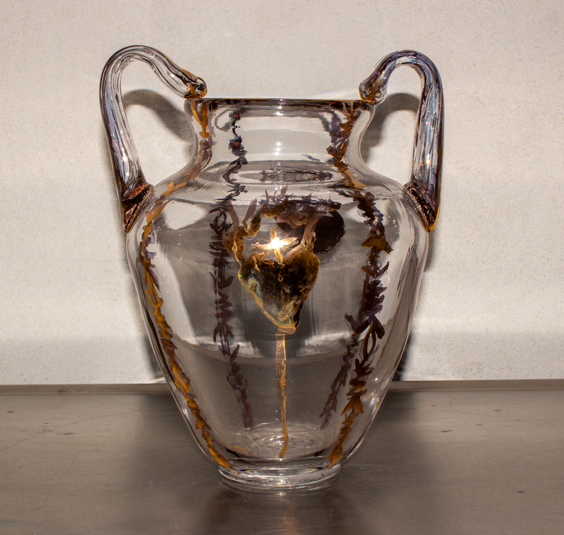 A clear glass vase with two handles, featuring brown and gold decorative accents.