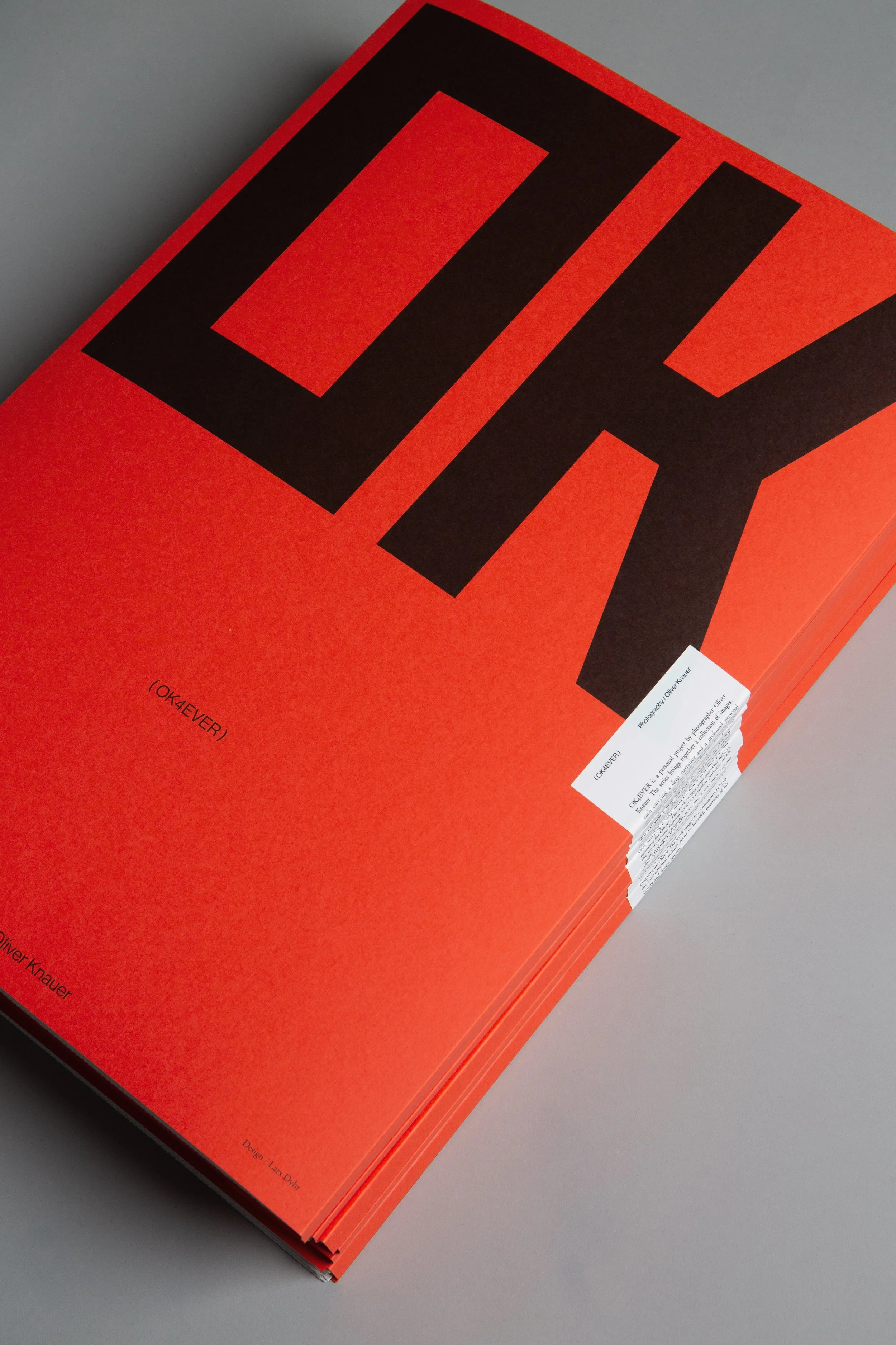 A open book with bright orange and black cover design, titled 'OK' on the cover.