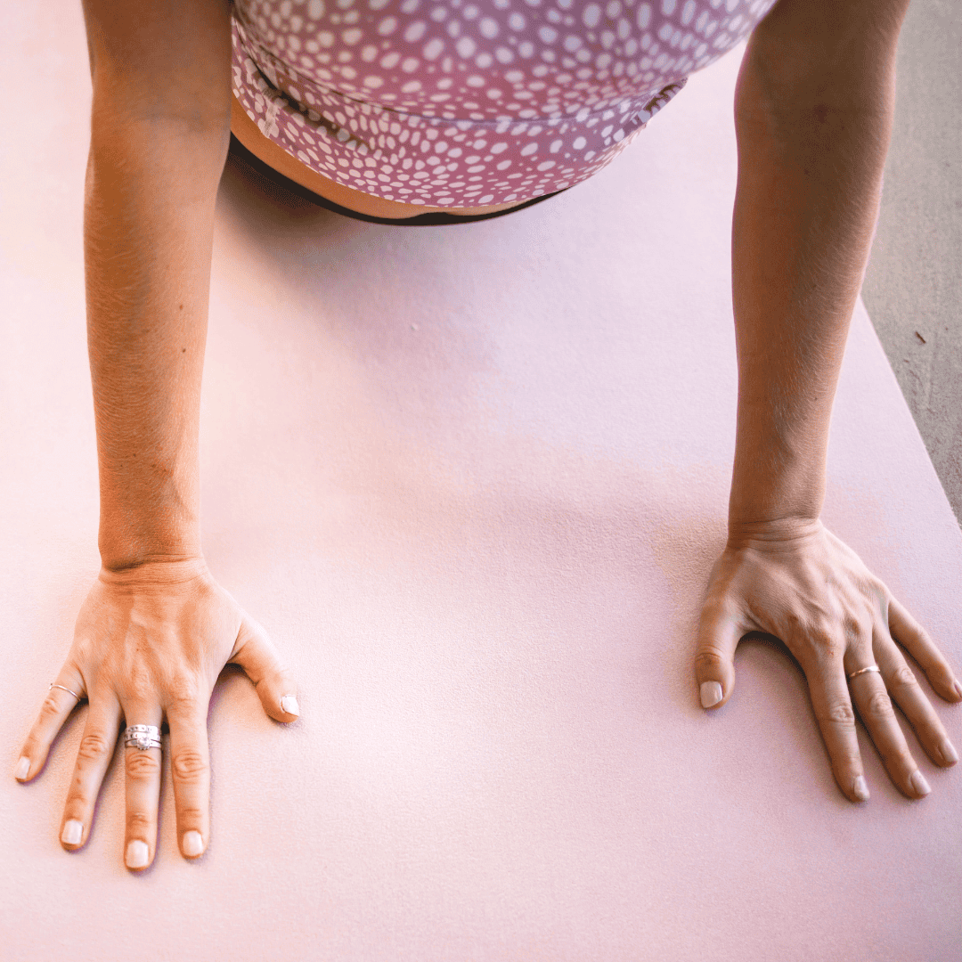 Close up of a woman's hands on a yoga mat.