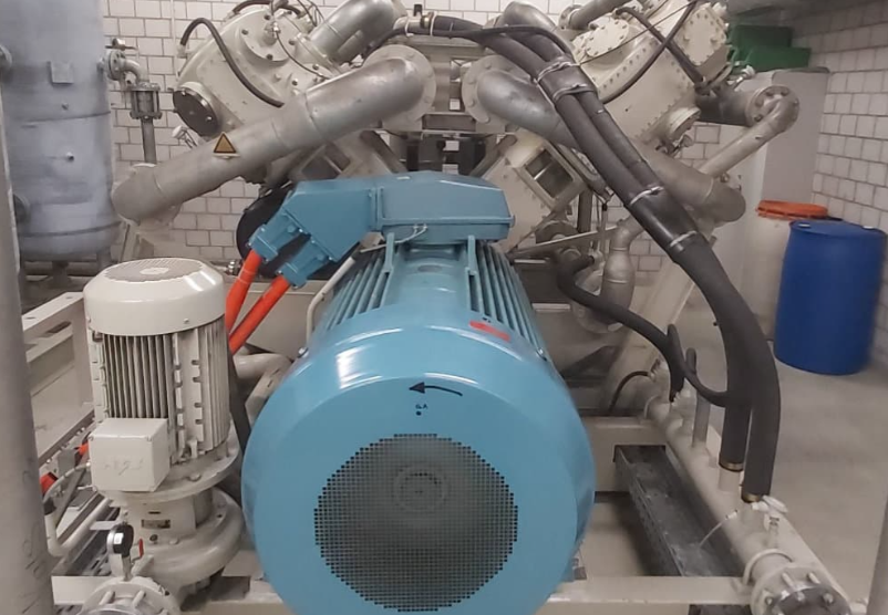 Industrial blue electric motor and connected metal piping in a mechanical equipment room