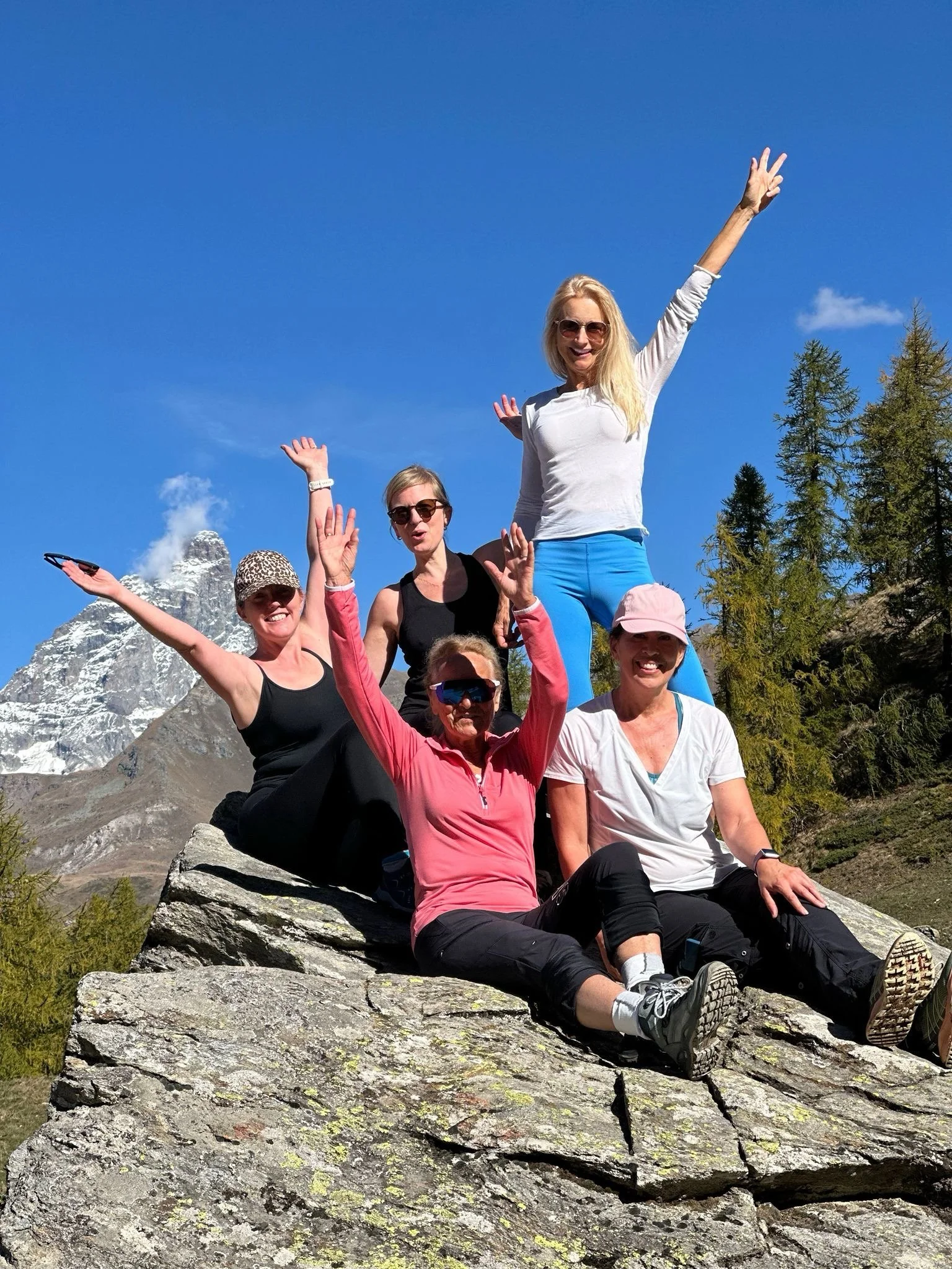 yogaweekenditaly girls are sitting on the top of the mountain Matterhorn in the background