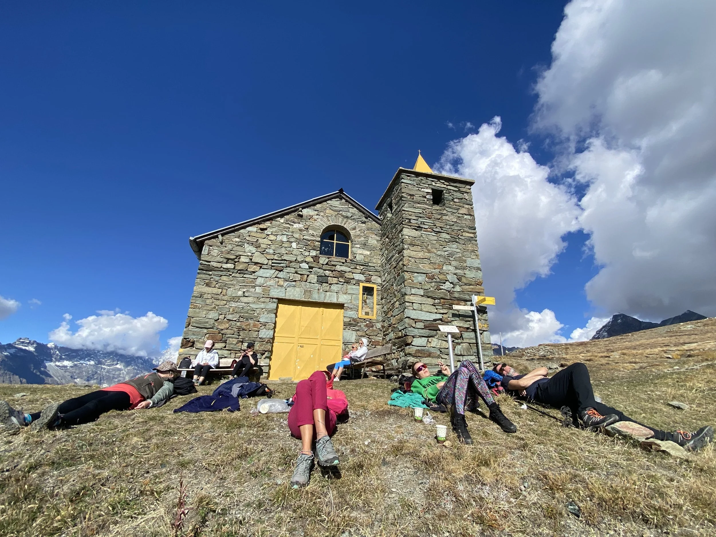 Aosta Valley Italy, old church on top of the mountain with girls relaxing after a hike