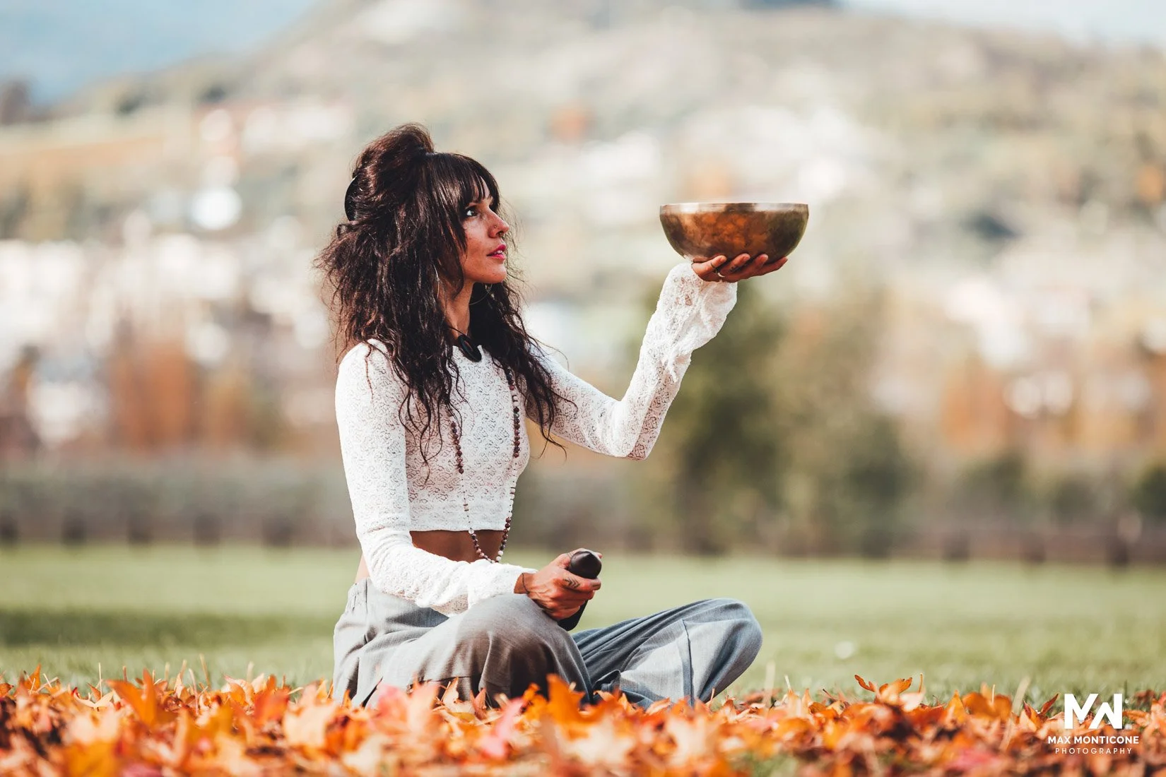 women practising yoga in nature wearing white short top and trousers, in autumn leaves in the Aosta Valley Italy