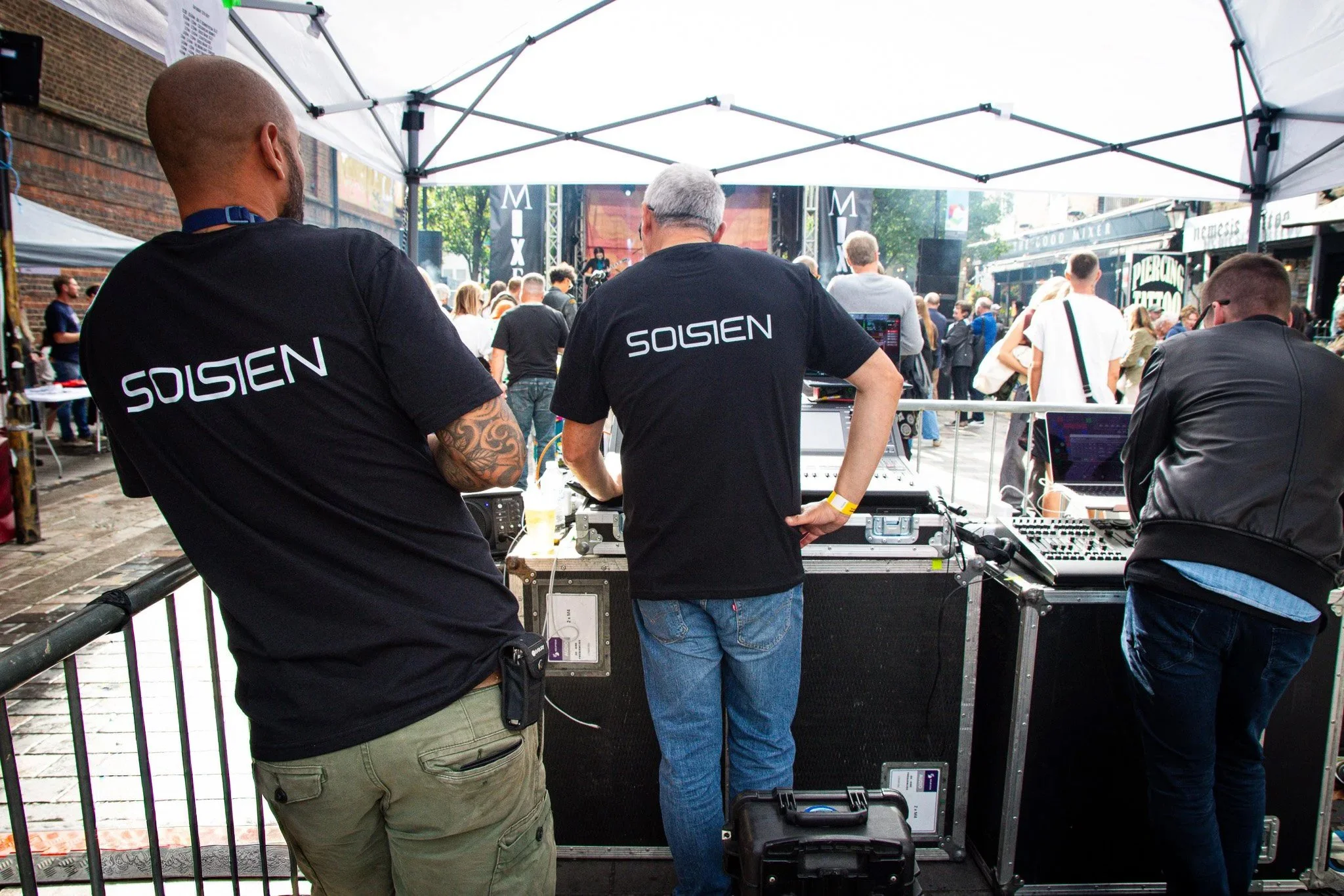 A team of sound engineers at a mixer desk at a a festival. Wearing branded Solsien clothing