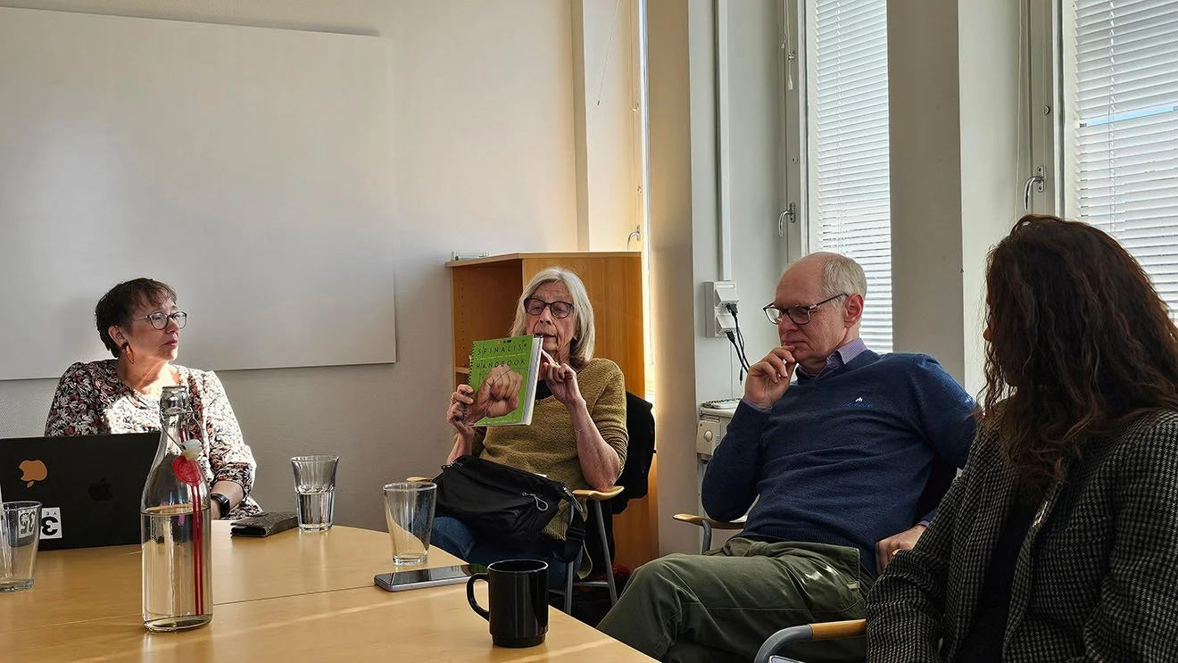 tre kvinnor och en man diskuterar och funderar kring ett bord